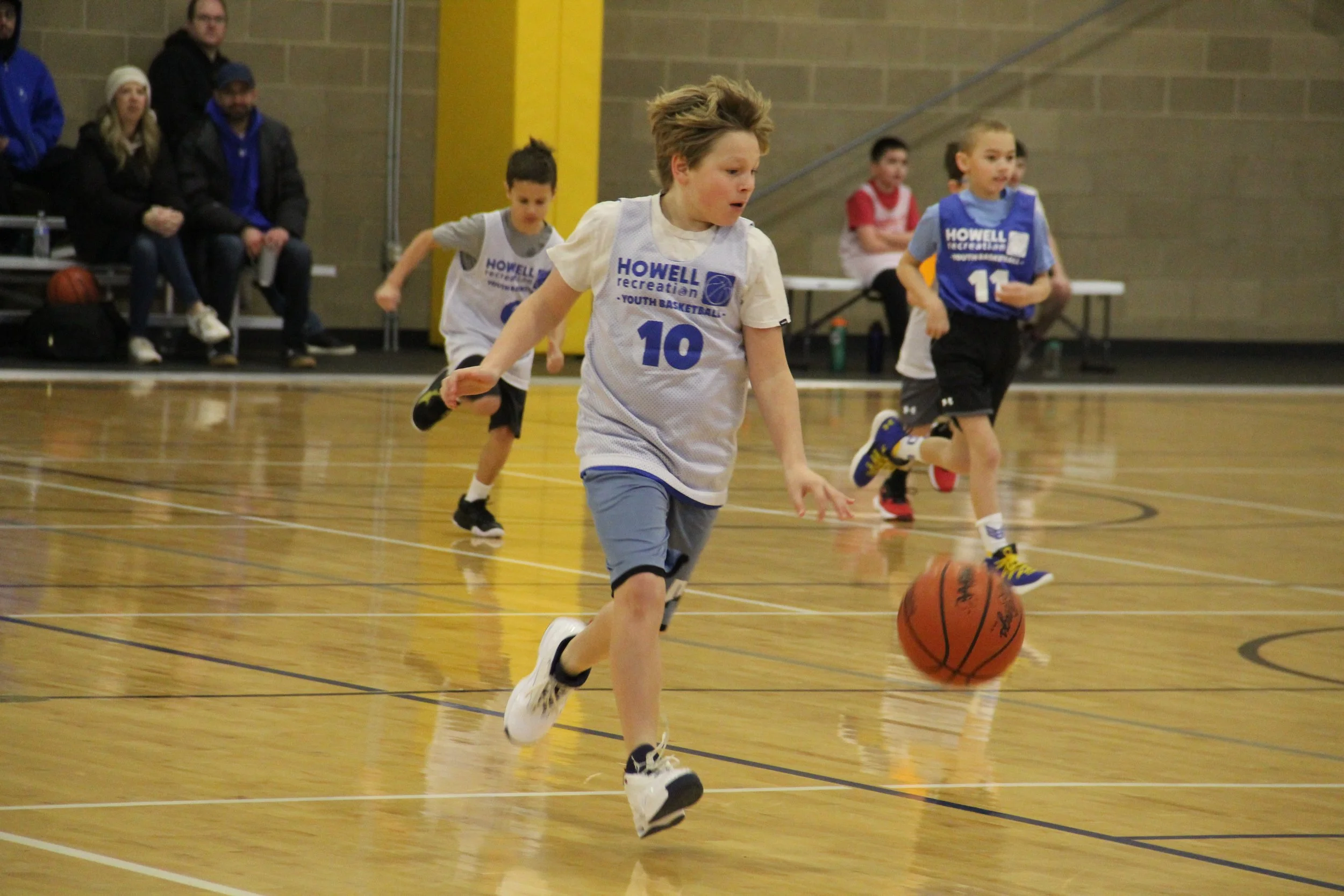 A photo of a boy dribbling a basketball in the Howell Recreation Boys Basketball League.