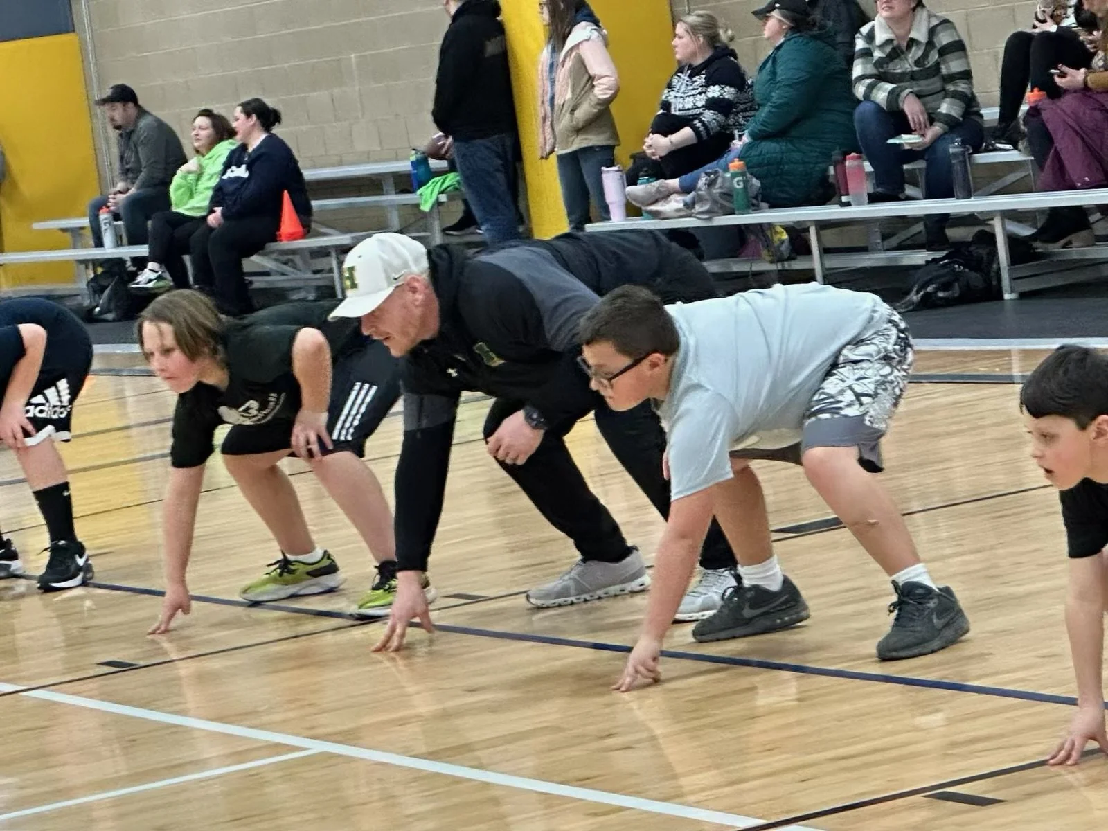 A coach and two boys hold a football starting position.