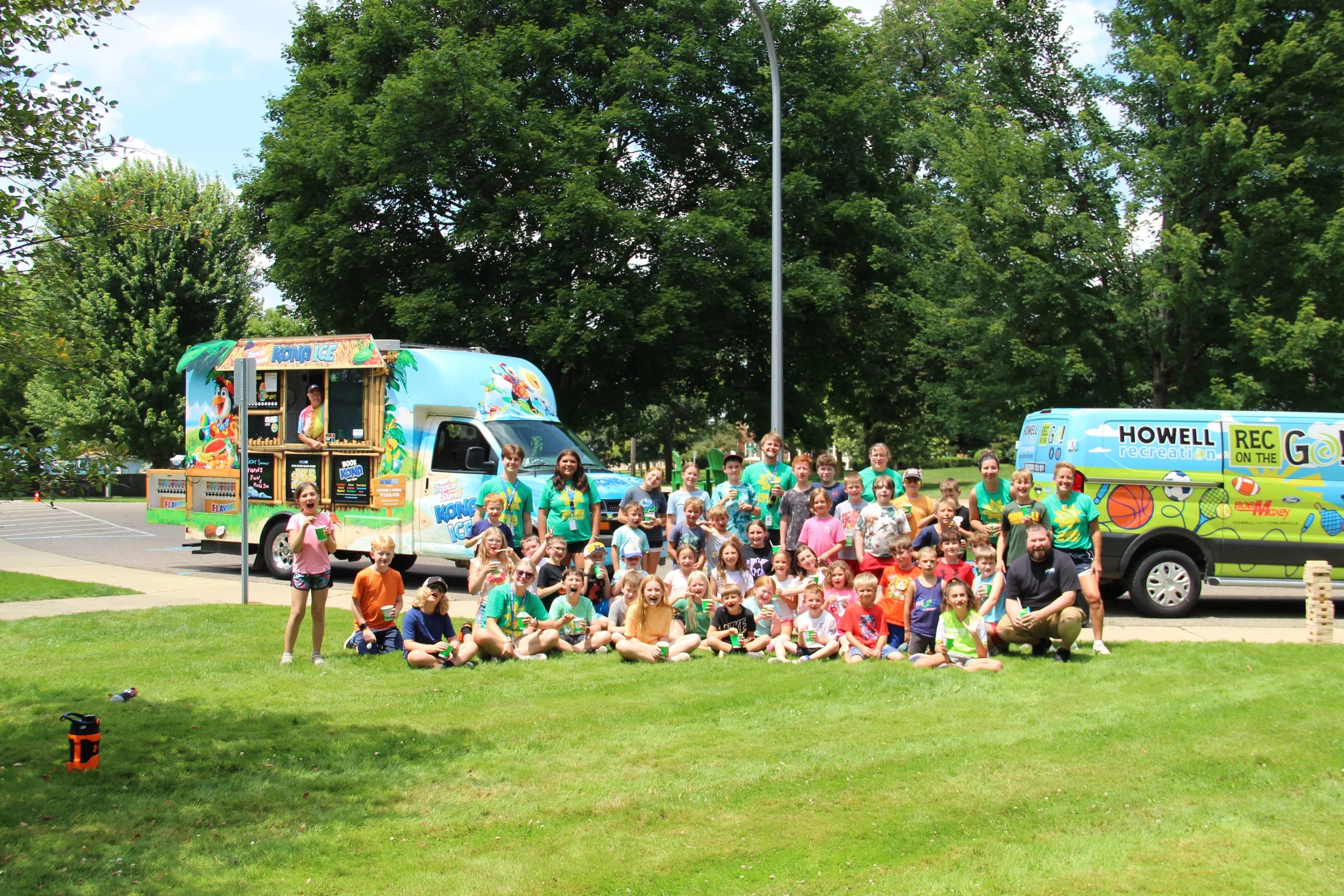 A group of kids eat shaved ice and smile in front of the Rec on the Go van.