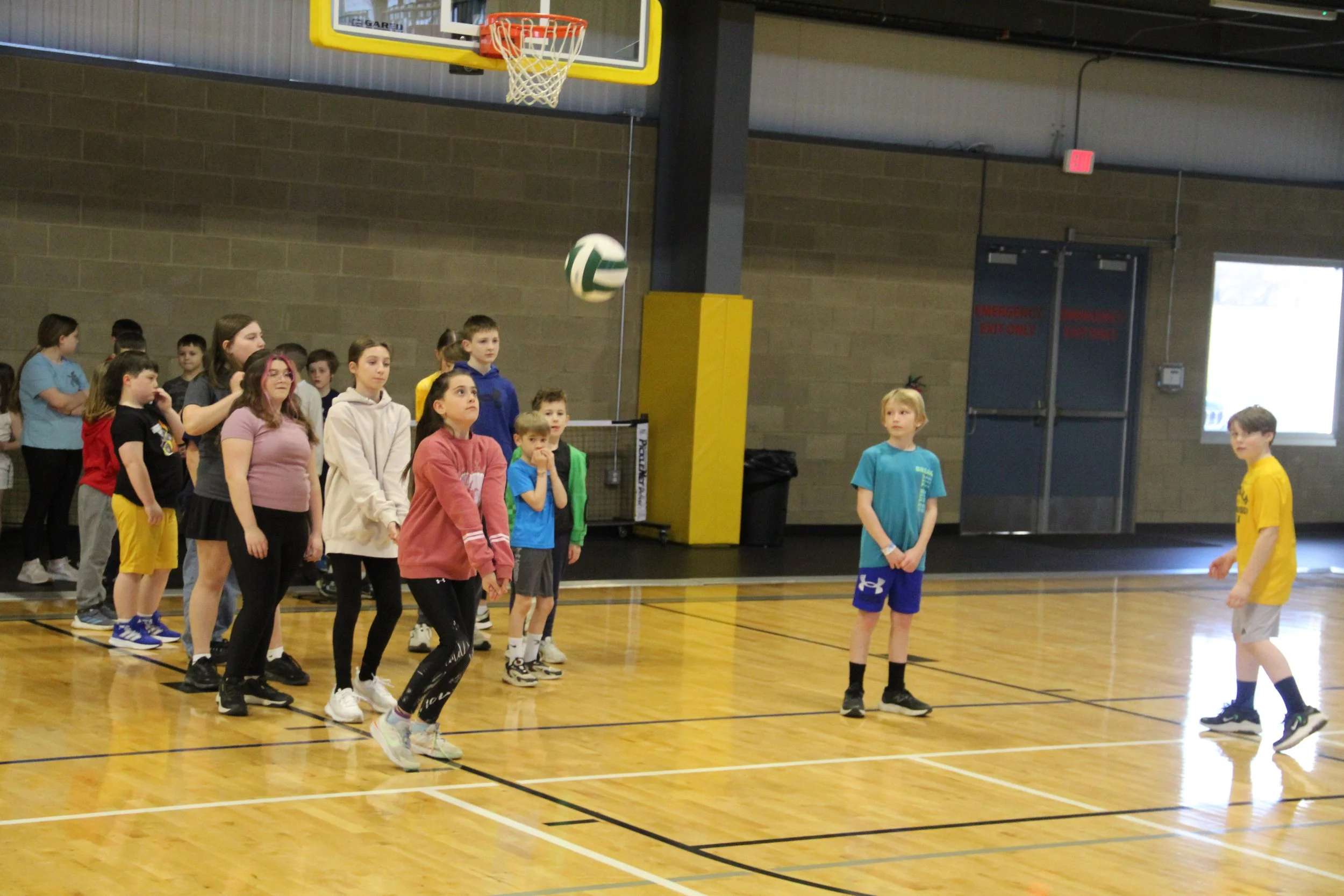 A group of kids line up to return a volleyball serve at Spring Break Sports Camp.