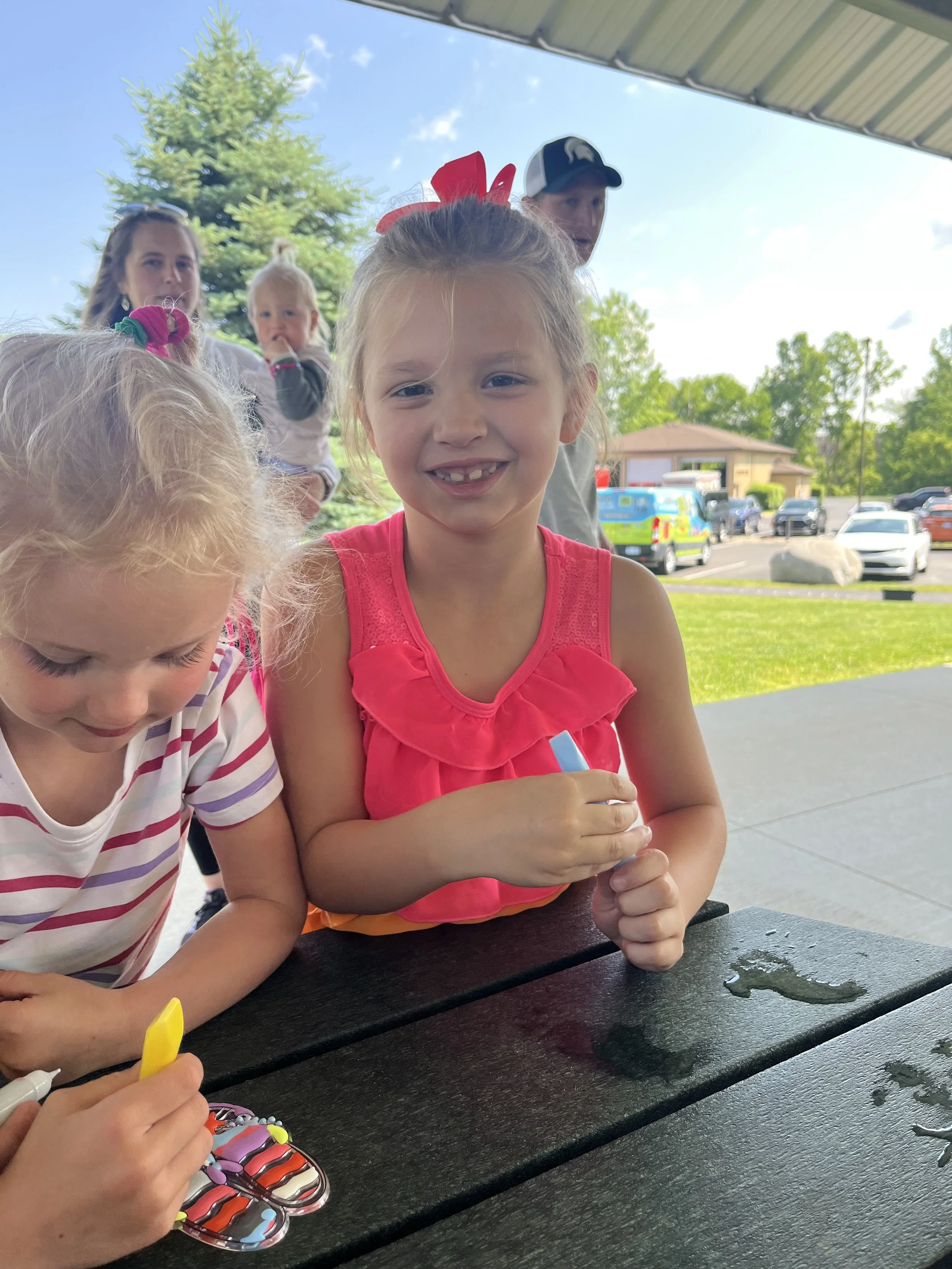 Two girls paint colorful sun catchers.