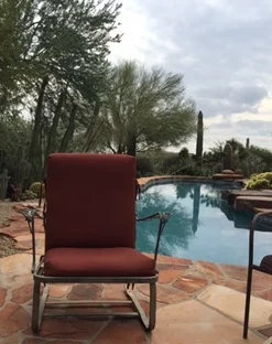 Imagine you are looking at this scene, viewing the chair with the pool. You are sitting in a chair opposite the red chair you see in this photo.