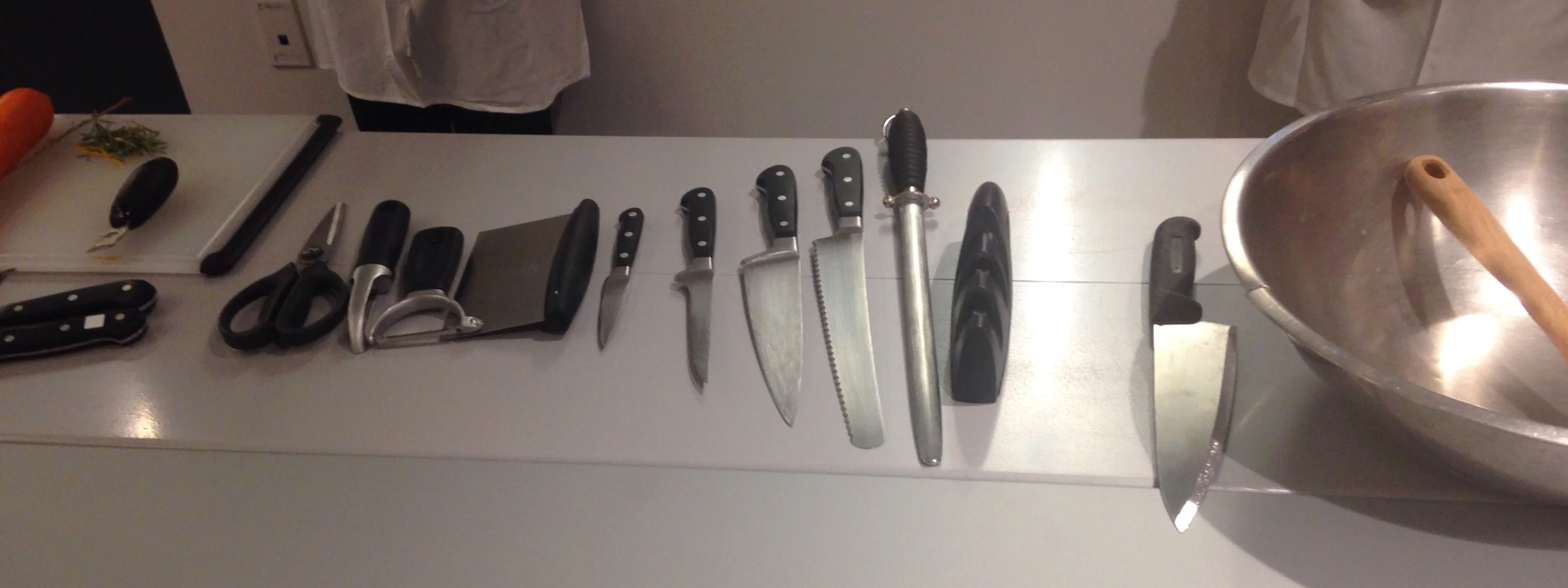 Shears, a peeler (you only need one - not both), a scraper, a paring knife, a deboning knife, a 6" chef's knife, a serrated knife, a honing steel, a sharpener and an 8" chef's knife