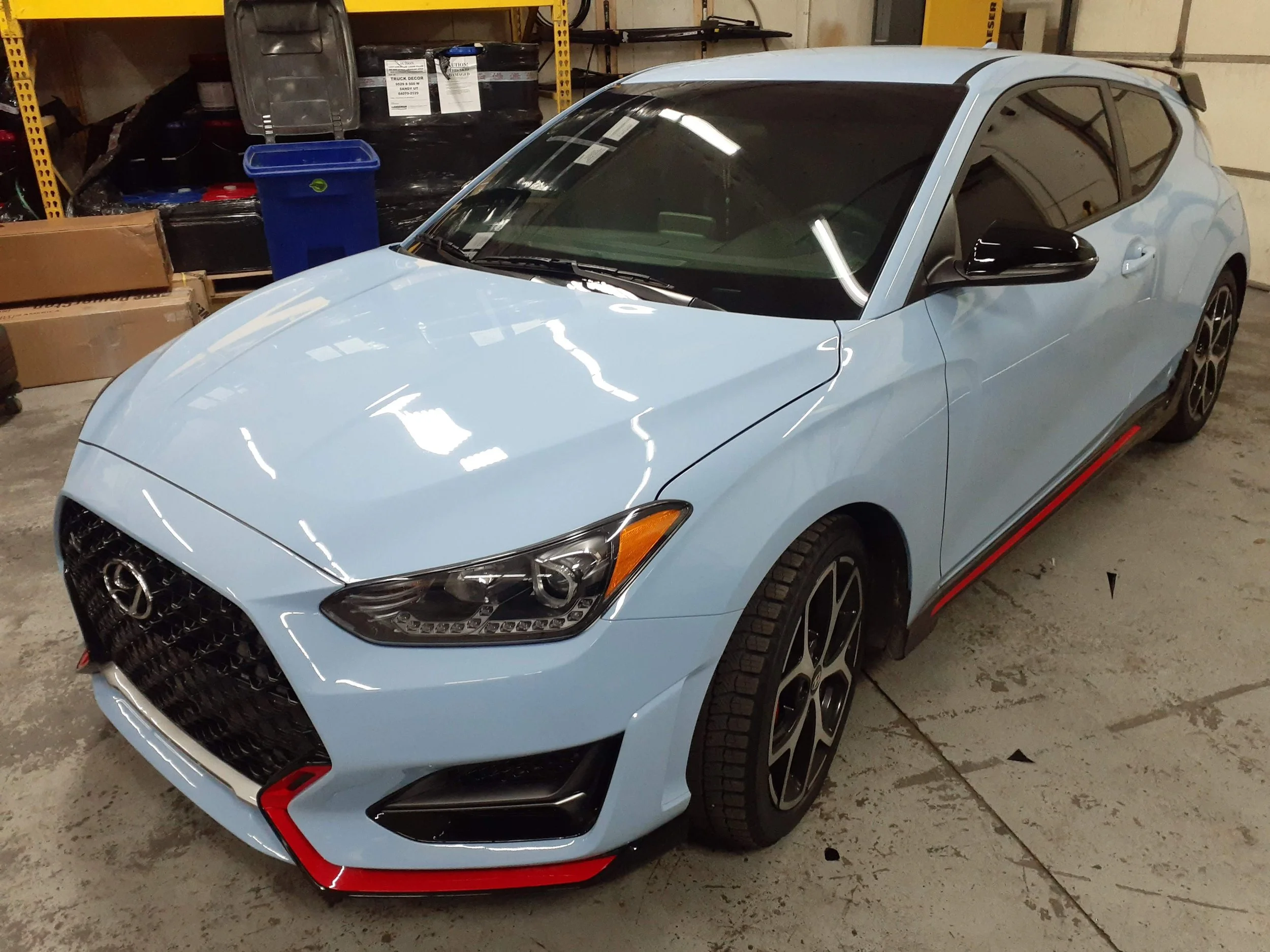 Light blue sports car with black and red accents parked in a garage setting.