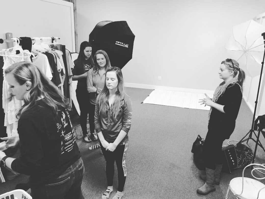 Molly preps hair and makeup. Holly Butterfield at right waits patiently to help girls get their clothing.