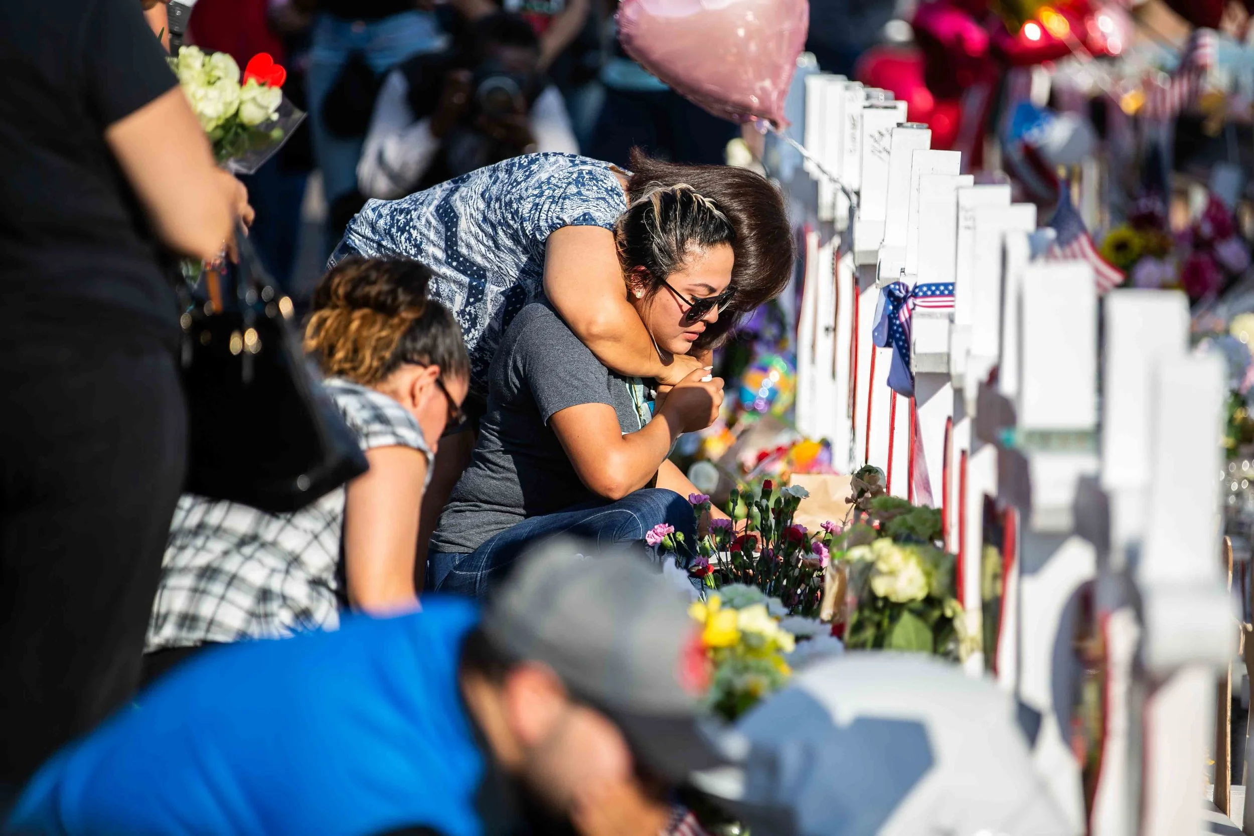 Pleople gather near the scene where crosses with the names of the victims of the mass shooting occurred in Walmart last Saturday morning have been placed to honor their memory in El Paso on Monday, August 5, 2019.