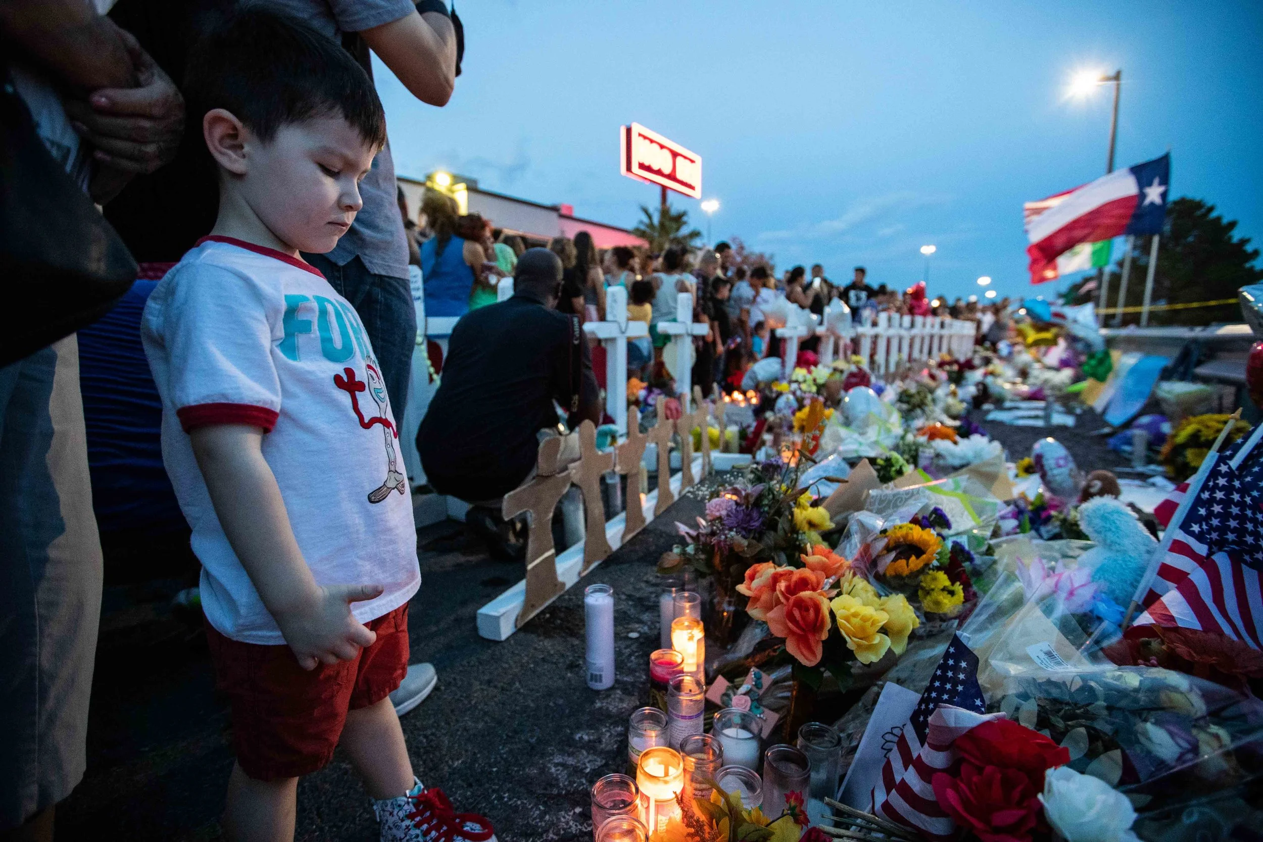 Roy Cedillo, 4, looks at some of the candles, flowers and flags that were placed on the scene to honor the victims of a mass shooting occurred in Walmart las Saturday morning in El Paso on Monday, August 5, 2019.