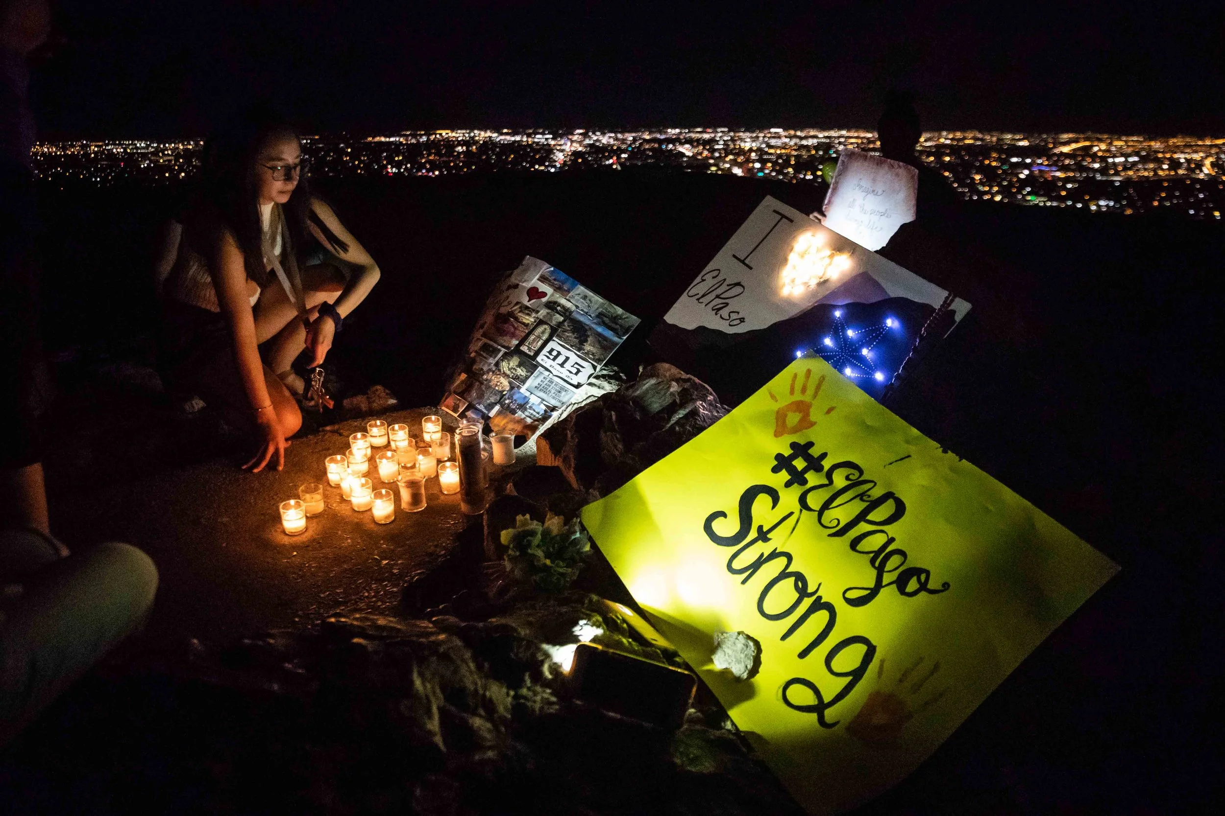 Chloe Trujillo sits next to some posters and candles that were placed at the Scenic Drive - Overlook to honor the victims of the mass shooting occurred in Walmart last Saturday monirng in El Paso on Monday, August 5, 2019.