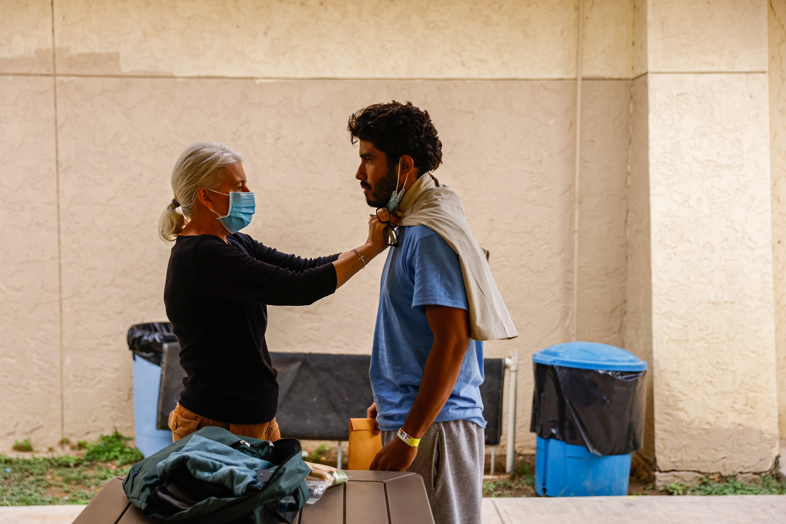  Tiffany Burrow, Director of Operations for the Val Verde Border Humanitarian Coalition, fits Víctor Rodríguez, 26, into shorts so he can have clean clothes before taking a bus to the East Coast in Del Rio on April 20, 2022. Rodríguez, originally fro