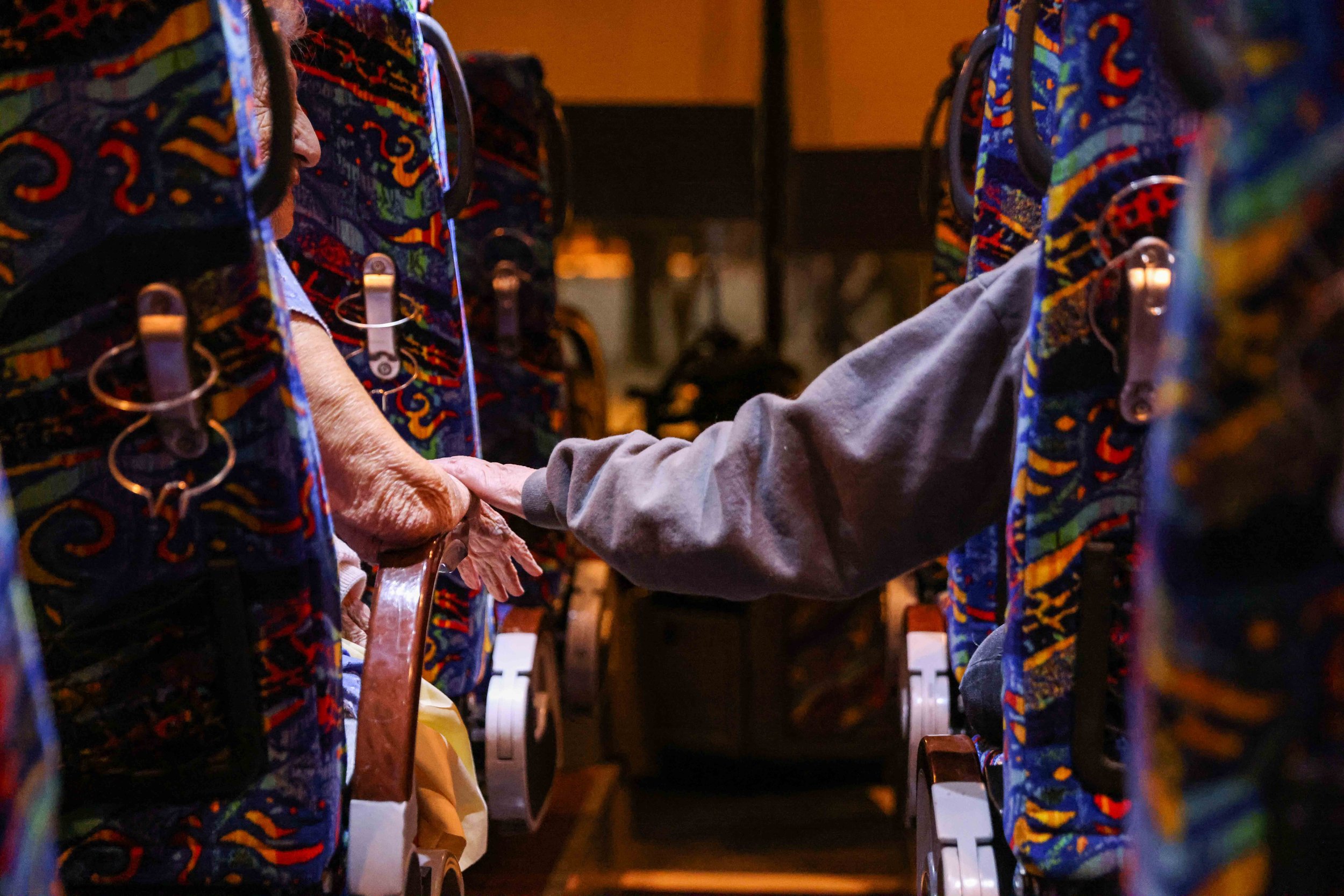  Gloria Sanders, 76, reaches for her mother's arm, Maria Barajas, 100, as it rests on the armrest of her seat to try to calm her down as they prepare to spend the night on the bus that serves as warming center located in Pleasant Oaks Recreation Cent