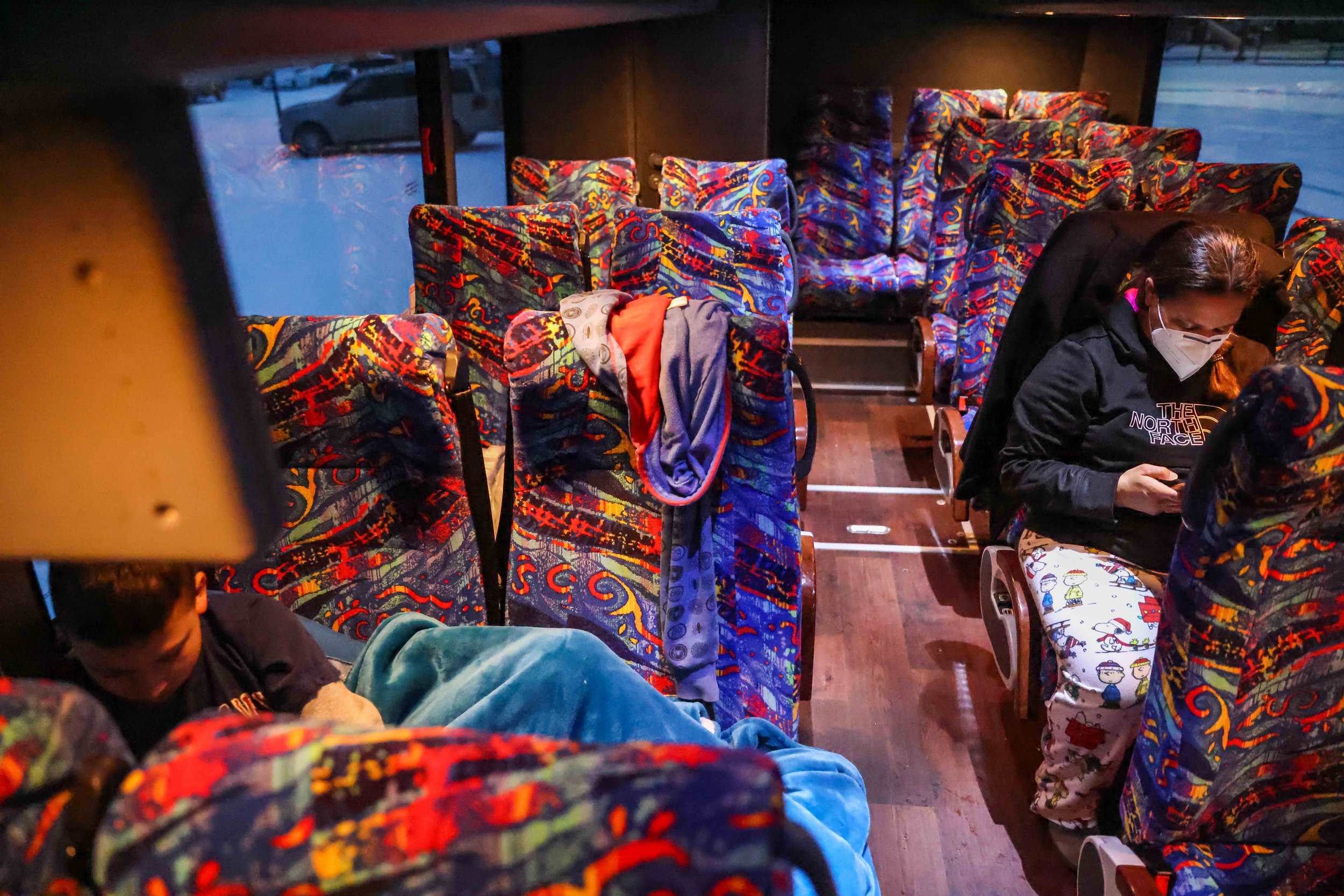  Marleny Almendarez, 38, checks her cell phone as her son, Aaron Hall, 11,  who is on the spectrum, makes himself comfortable to spend their second consecutive night at the the bus that serves as a warming center located in Pleasant Oaks Recreation C