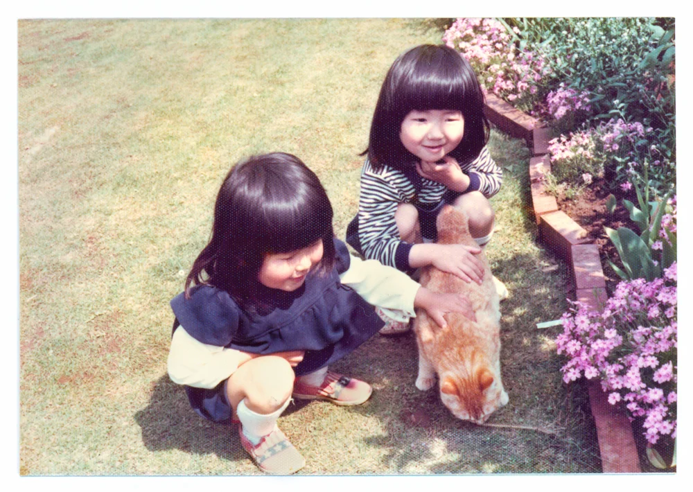 Seen here is Kyoko in the navy dress and in the stripe shirt is her sister. The orange cat's name was Ichibei who was their main cat growing up, best cat ever...