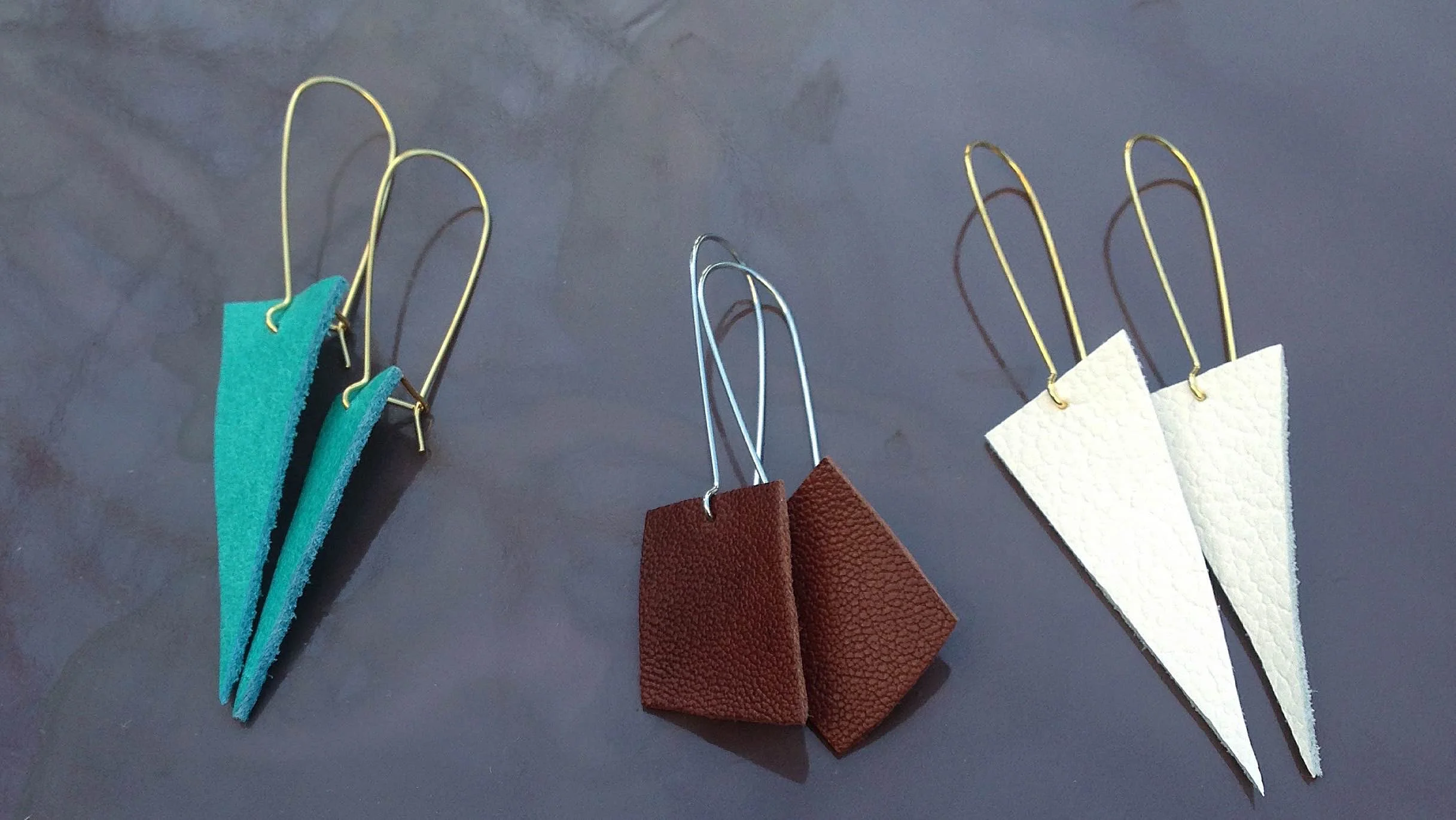  Hand-cut repurposed leather earrings on surgical stainless steel hoops. The leather is from high-end bag makers in San Francisco.   Note: all earrings have been painted with a clear acrylic glaze on the back and sides to smooth out the leather "fuzz