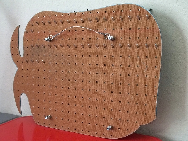 Backside of pegboard with wall spacers and hanging hardware.