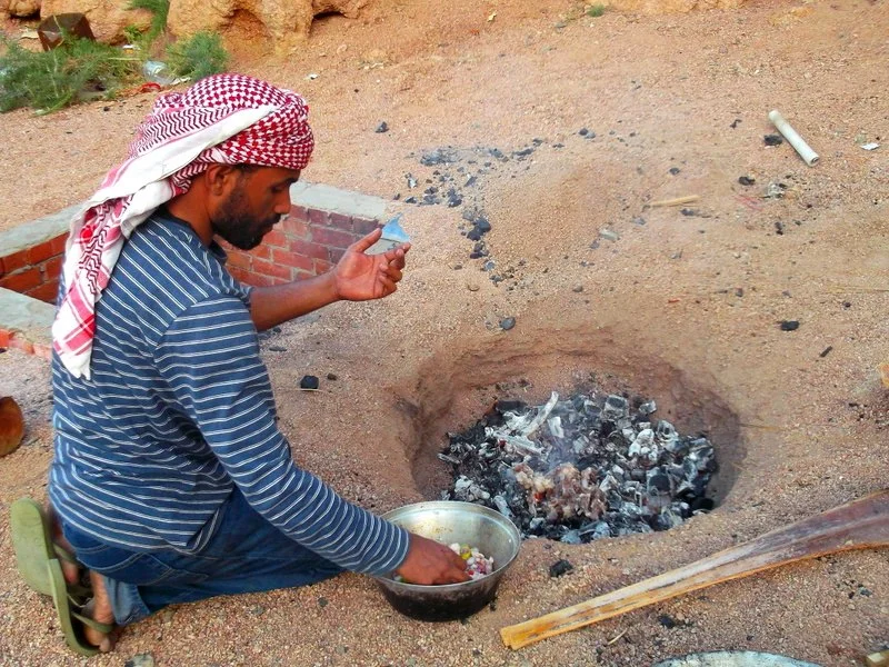 Mondi places the goat meat on hot ashes ready to be cooked for a few hours