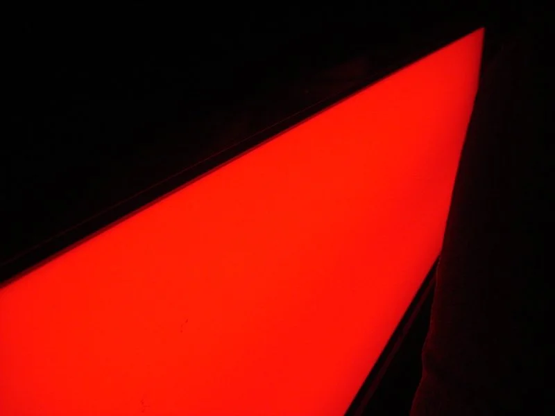 Close-up of a glowing red triangular light source in a dark environment.