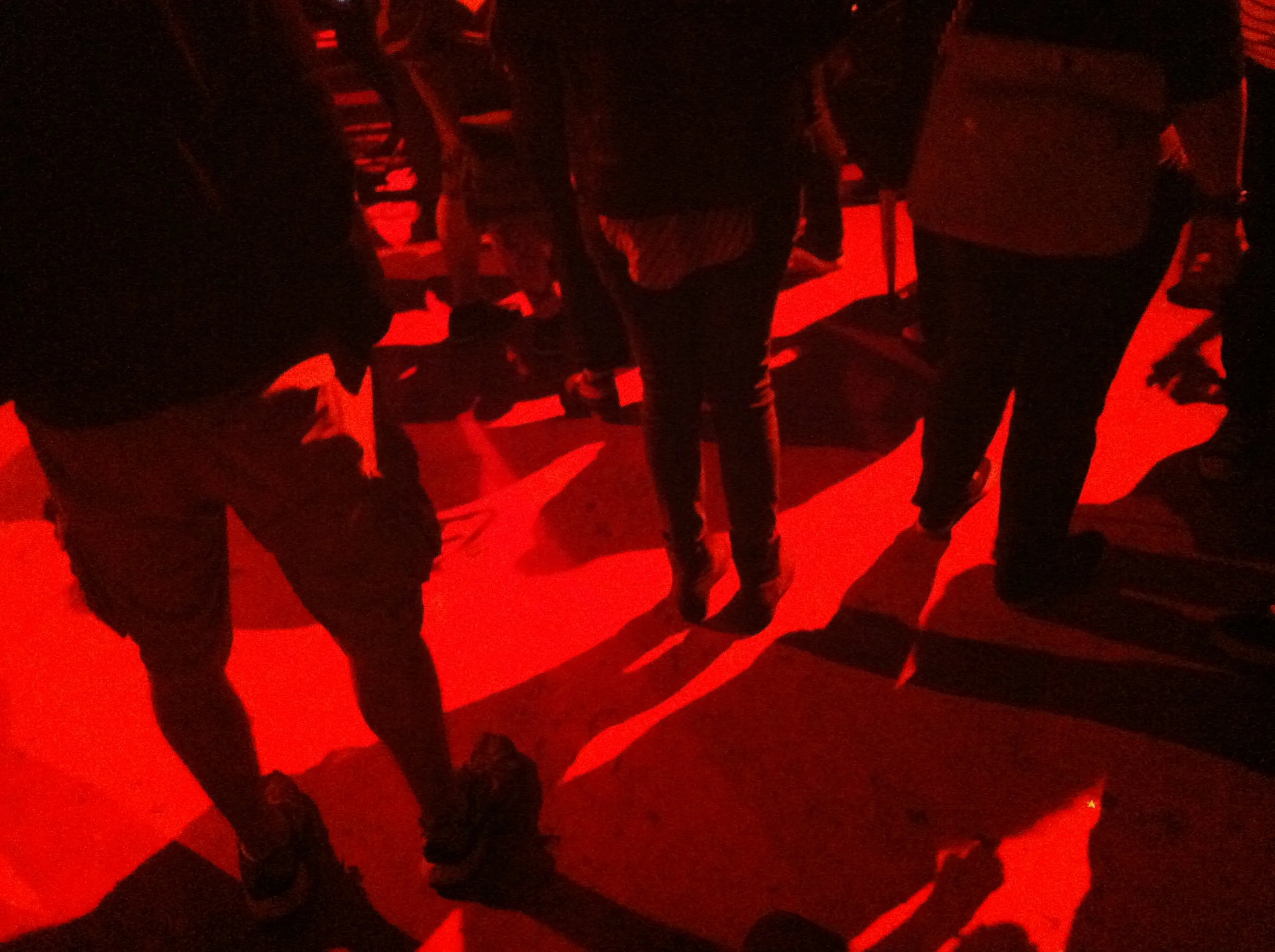 Group of people standing together in a dimly lit, red-colored room.