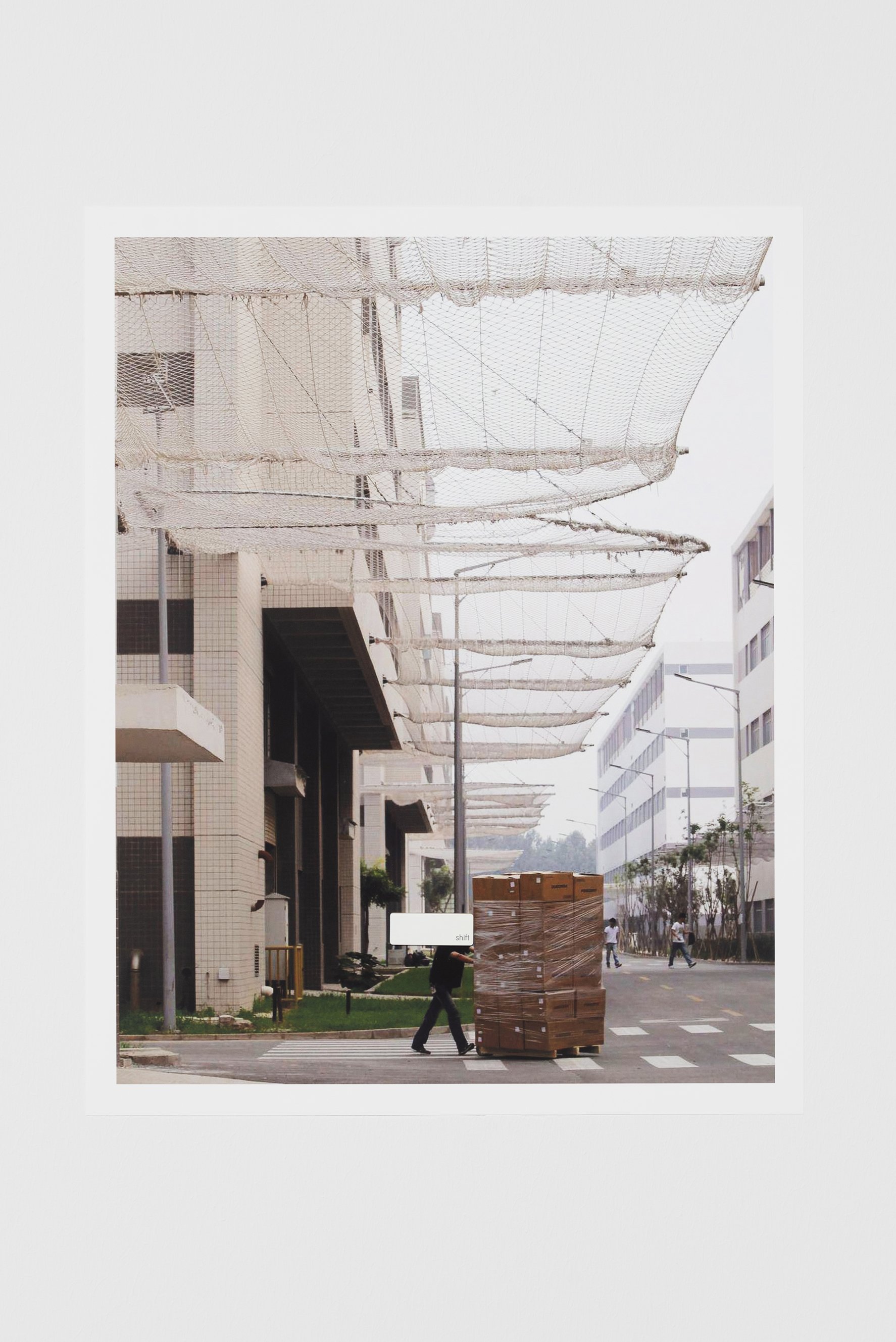   Maryam Jafri   Shift (No Lithium, No Work)  edition of 3 + 1 AP 2023 Archival inkjet print, key cap 16⅞ x 13⅜ in. &nbsp; 43.00 x 34.00 cm MJ0144.1  Worker at Foxconn campus with anti-suicide nets above  