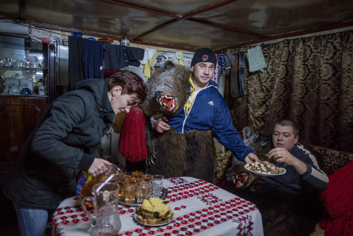  Cătălin Apetroaie, a bear in Toalaca's troupe, serves his fellow bears cubes pig fat, while his wife fills up glasses of homemade palinka liquor. The troupe has just finished performing at Apetroaie's home and is taking a rest before continuing to t