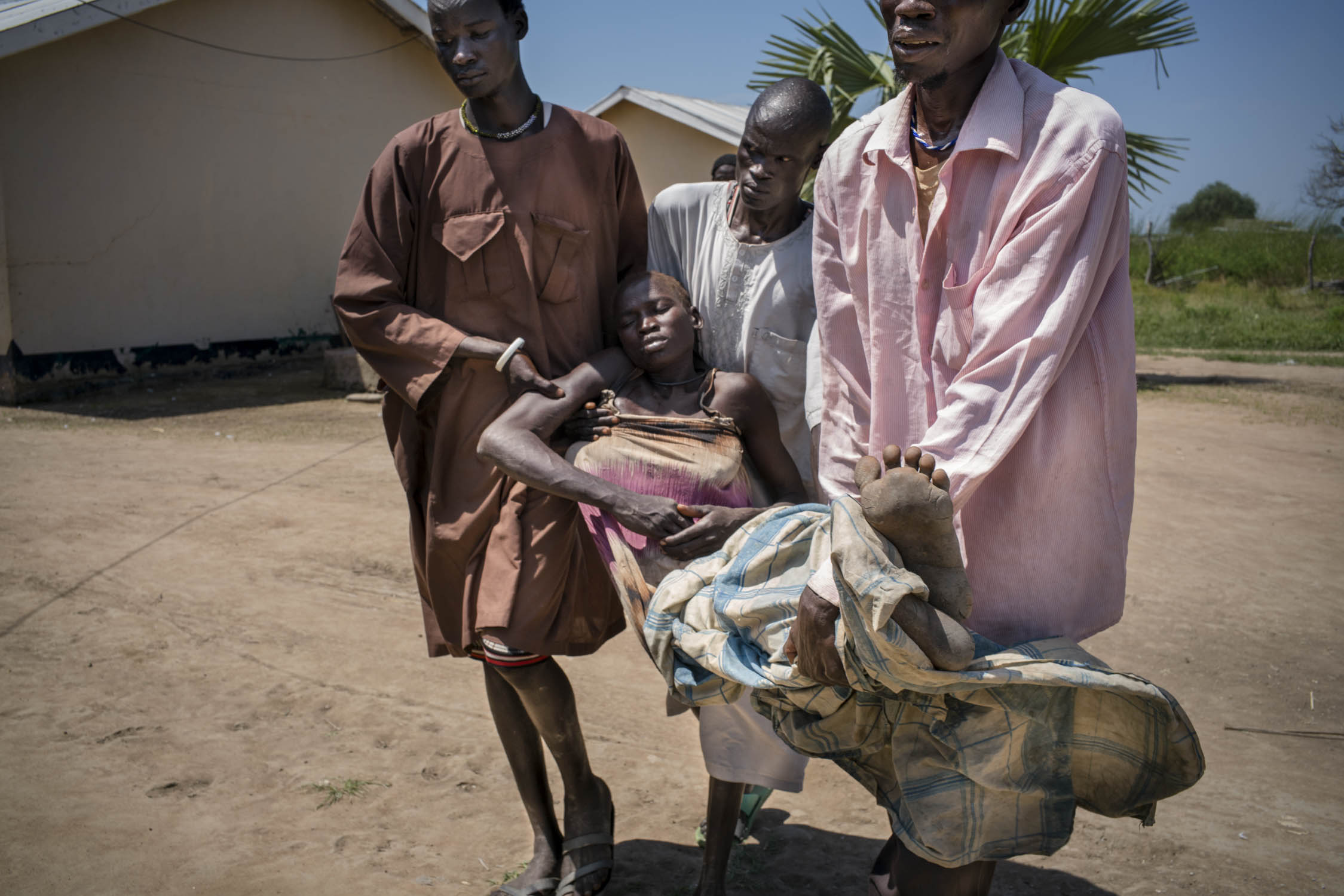  Arek Nuoi, 32,&nbsp;is carried unconscious by her three brother-in-laws to a ward at a government-run health care center, where she will receive urgent treatment for acute malaria. Her brother-in-laws transported Arek from their home village by plac