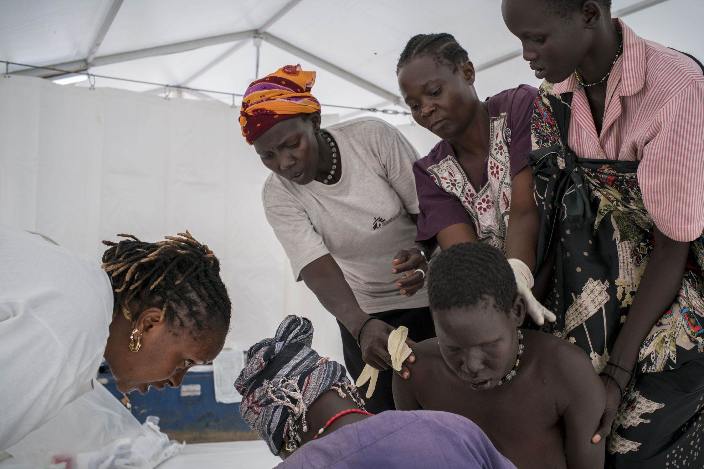 After an extremely difficult labor, a woman delivers her eighth child on her knees,&nbsp;assisted by a midwife,&nbsp;Rebecca, and her four assistants in a MSF hospital tent in the internally displaced persons (IDPs) camp in Bentiu. South Sudan has t