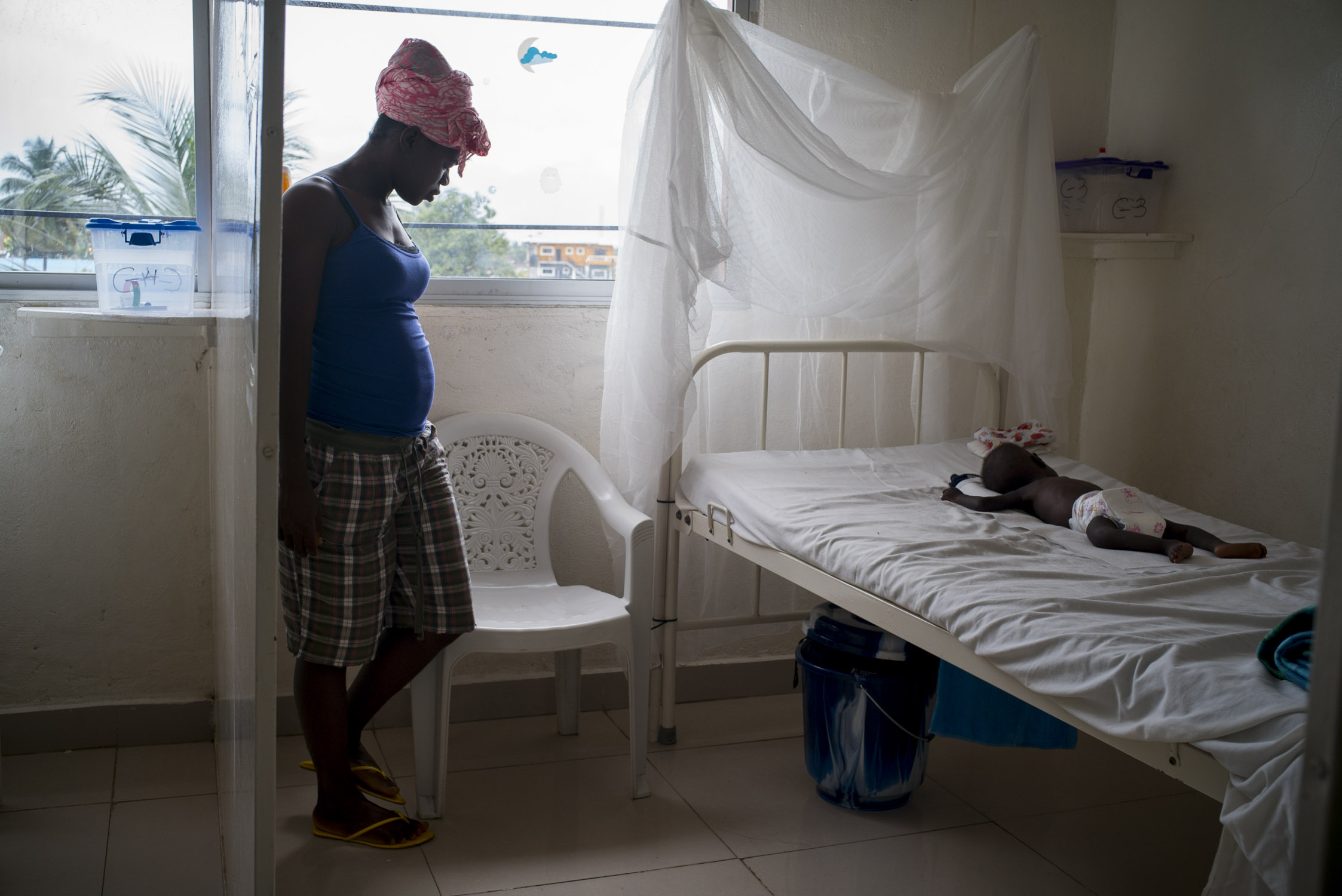  A mother stands bedside as her infants sleeps in the malnutrition ward of the MSF Hospital in Monrovia, Liberia. Sept. 27, 2016 