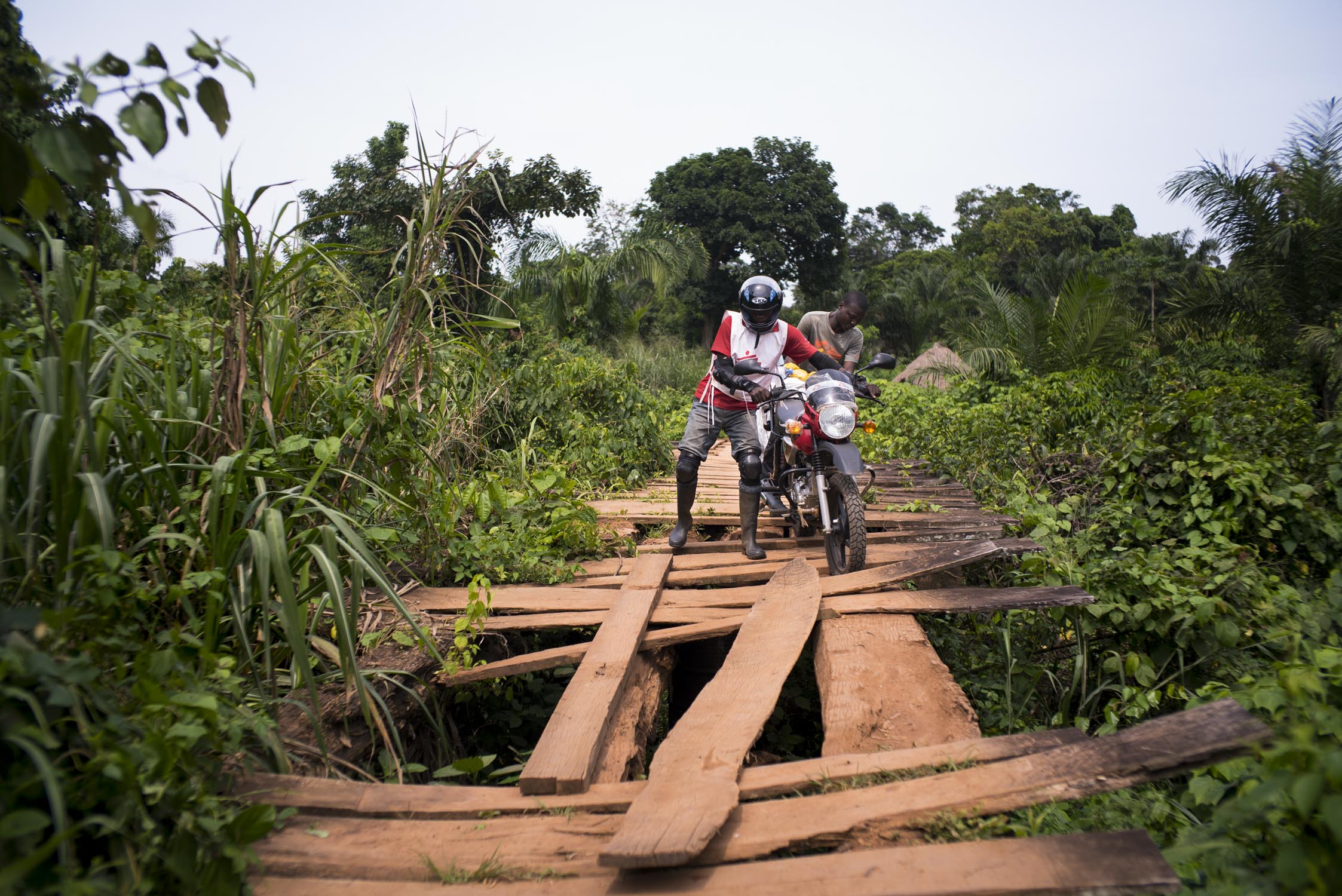 A MSF driver struggles to push his motorbike over a bridge on the route to the health center in the village of Nzeret, the epicenter of a measles epidemic that spread through this remote northern area of Democratic Republic of the Congo (DRC)&nbsp;i