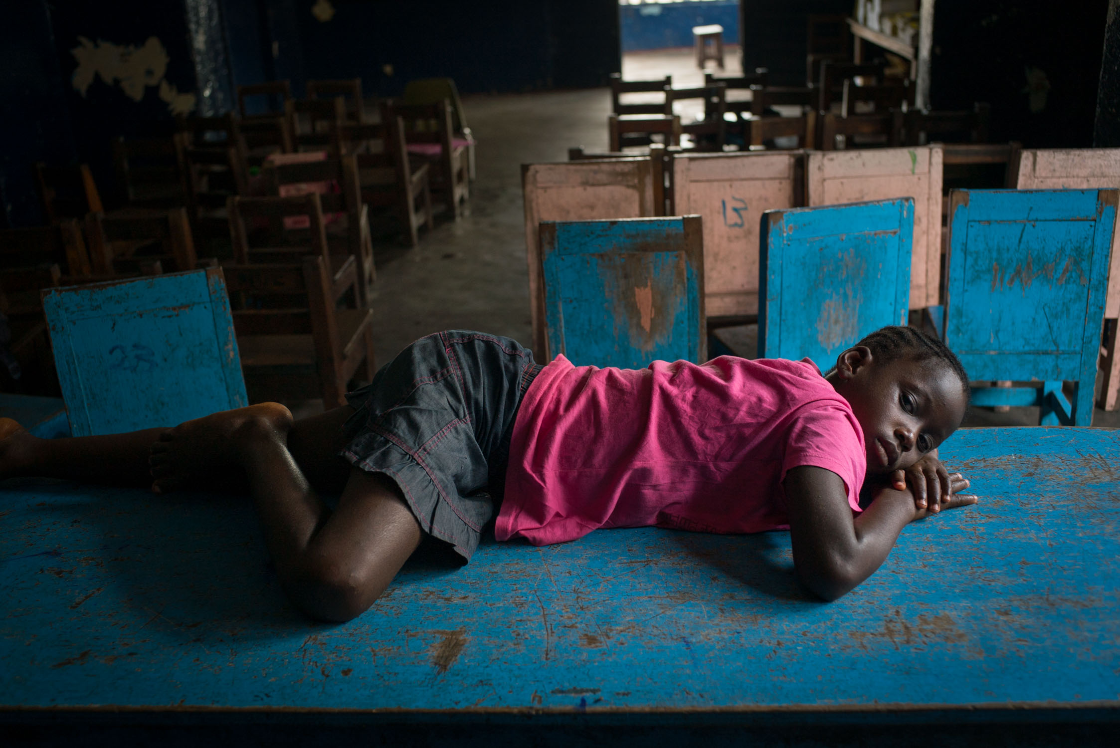  A youg girl suffering from malaria lies on a table after the classroom empties out at a Bridge school. One of the challenges to education in the developing world is that children come to school sick, so good schools usually supply medical referrals 