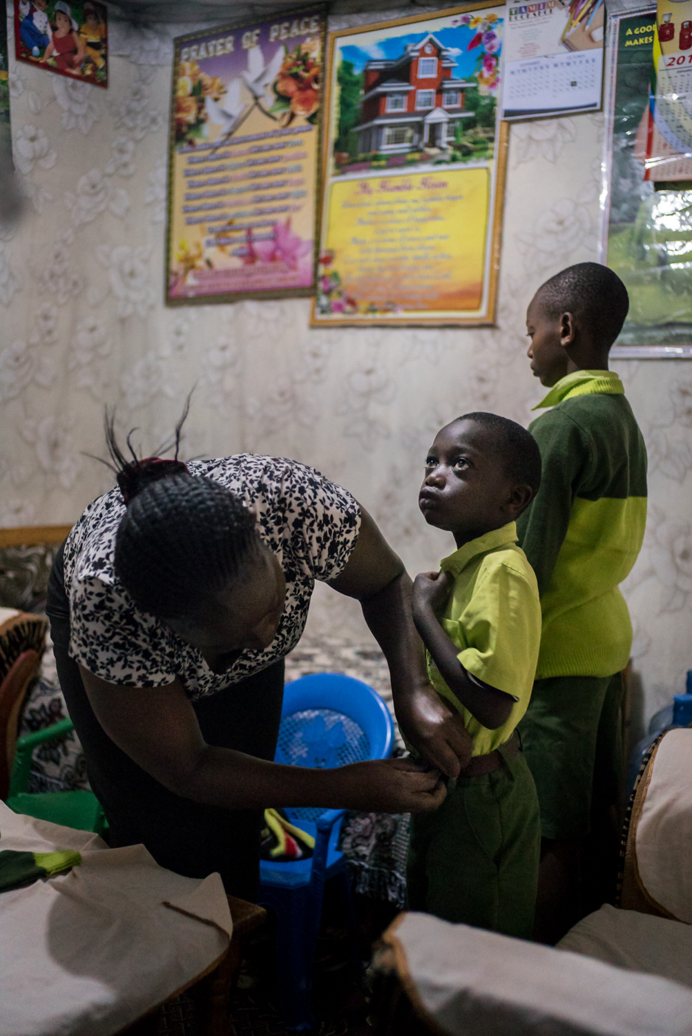  Elizabeth Mumo prepares her sons Samuel, 6, and Joshua, 12, for another schoolday at Bridge. She and her husband save to pay school fees for her two sons to attend Bridge, believing that since the school is run by white westerners, her children are 