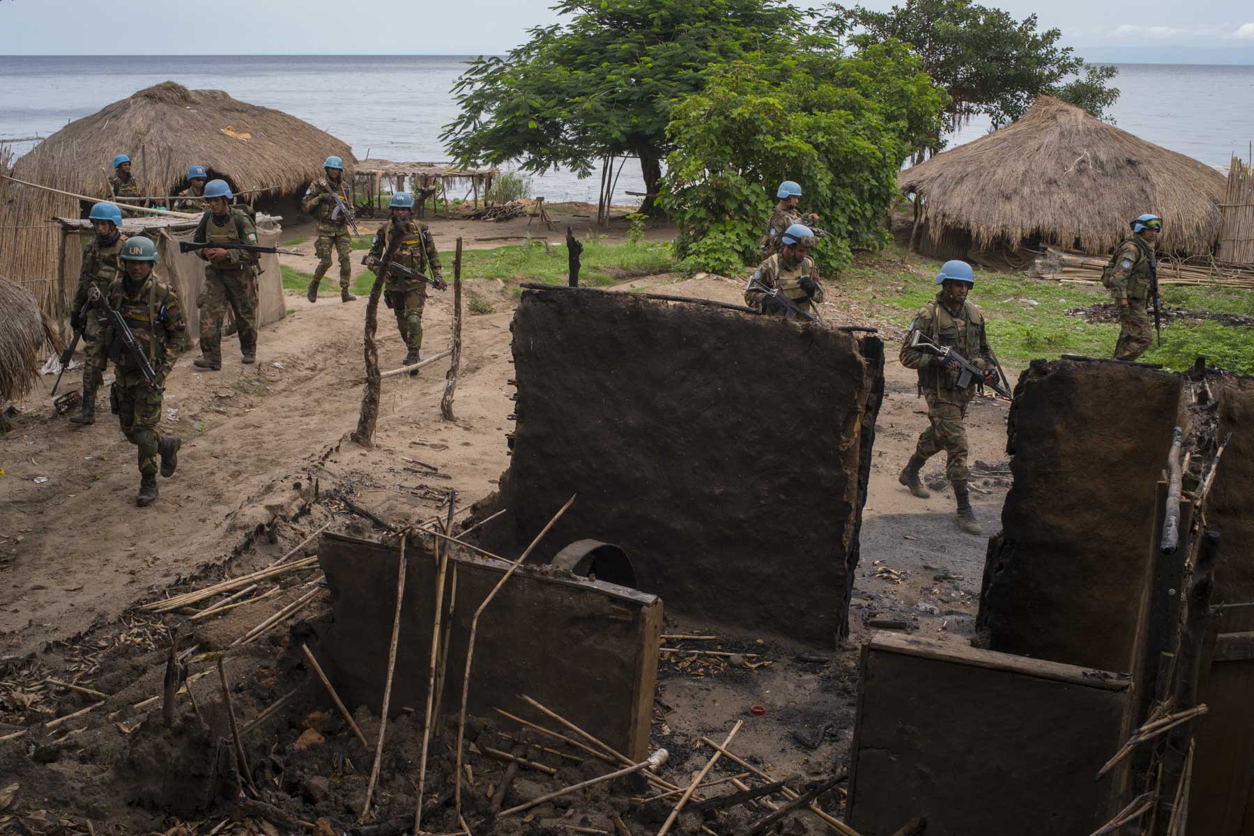  Soldiers from the Armed Forces of the DRC, and UN peacekeeprs from the Uruguyan and Bangladesh batallions move through Ghat, a deserted lakeside village that lies in ruins after attacks from militias less than a week prior. They have come here to me