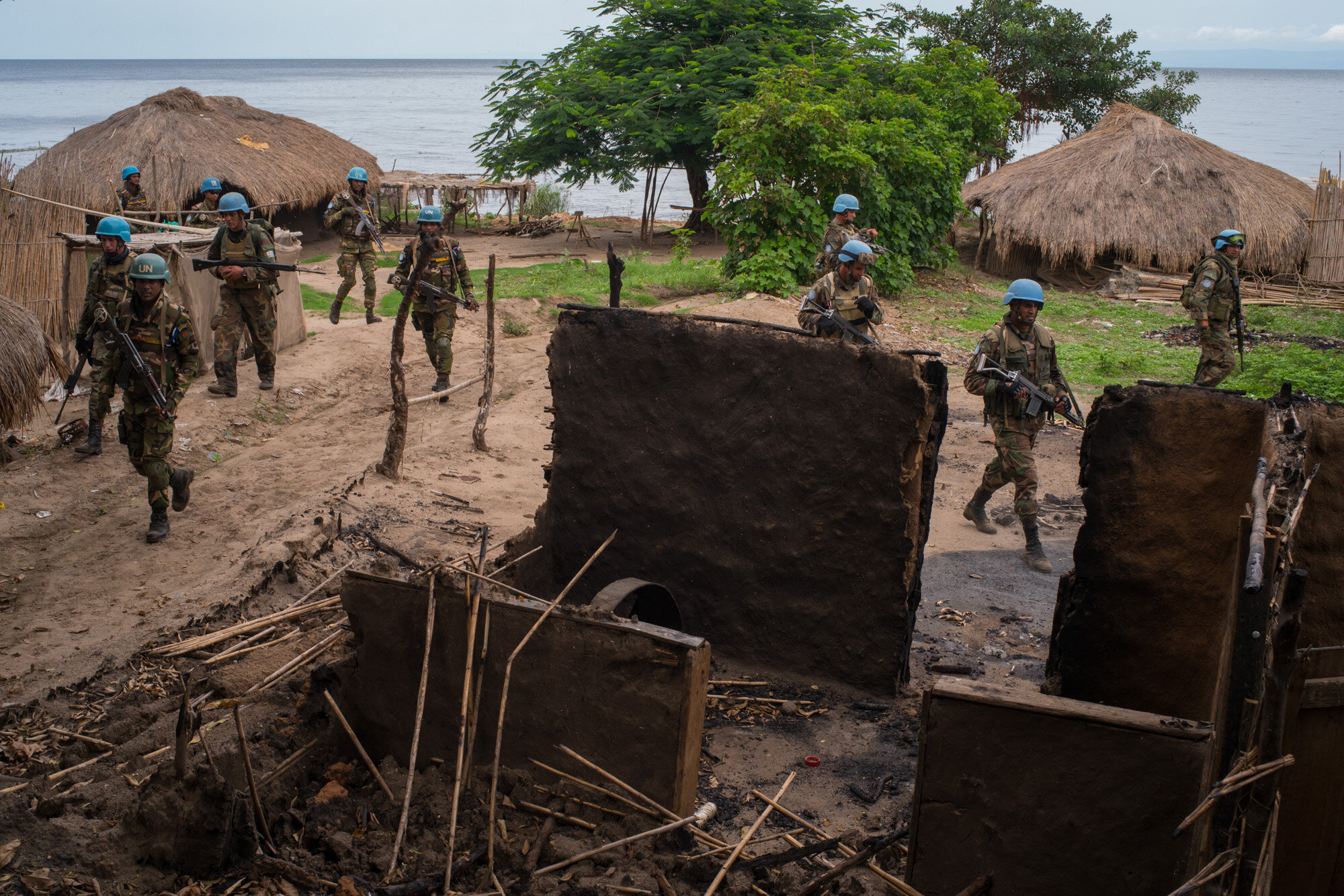  Soldiers from the Armed Forces of the DRC, and UN peacekeeprs from the Uruguyan and Bangladesh batallions move through Ghat, a deserted lakeside village that lies in ruins after attacks from militias less than a week prior. They have come here to me