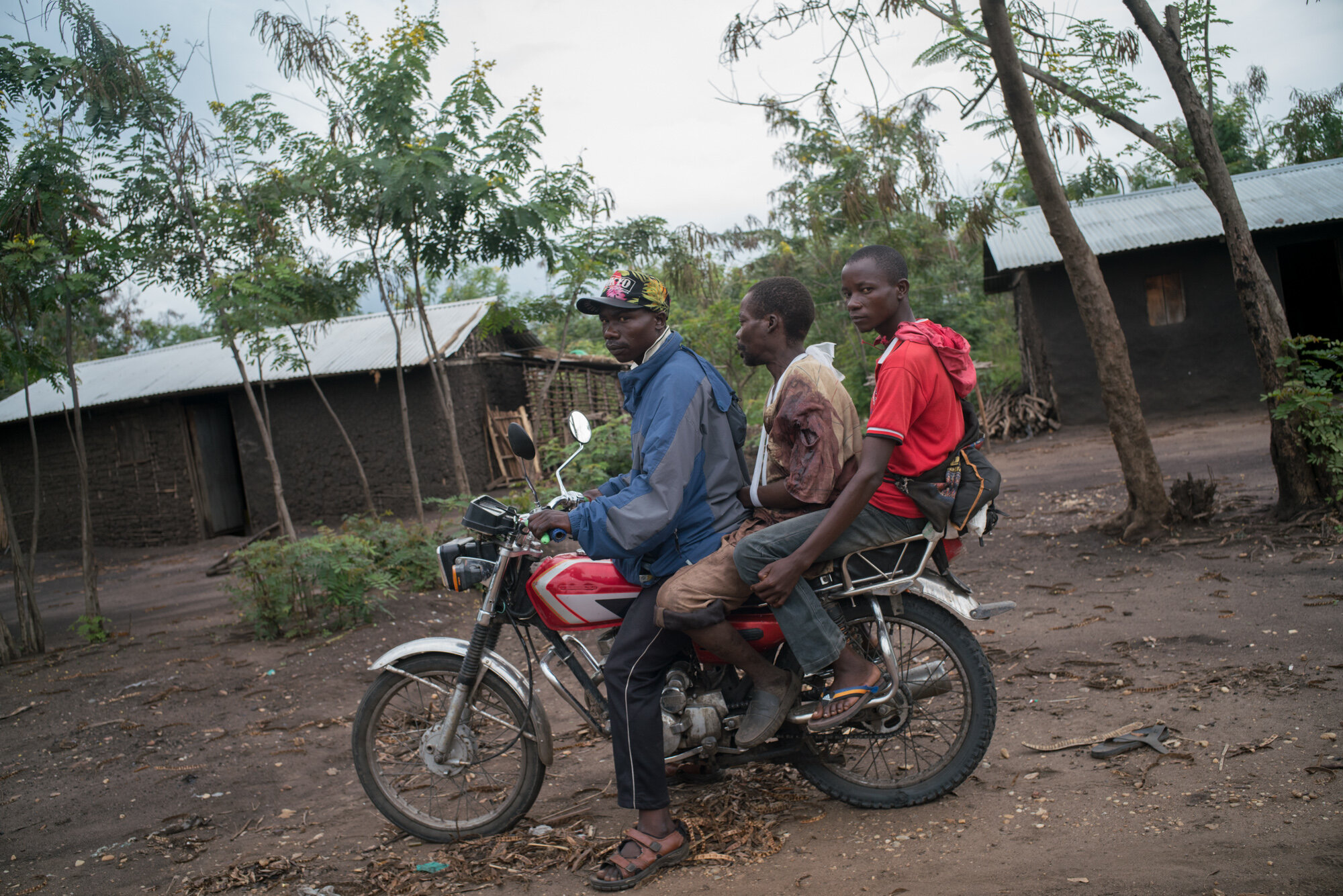  Villagers transport a man out of Nyamamba village, where he had been hiding in the nearby bush when militias found him and shot him. Nyamamba lies in ruins after attacks a week prior. March 18, 2018. Nyamambda, Ituri province, Democratic Republic of