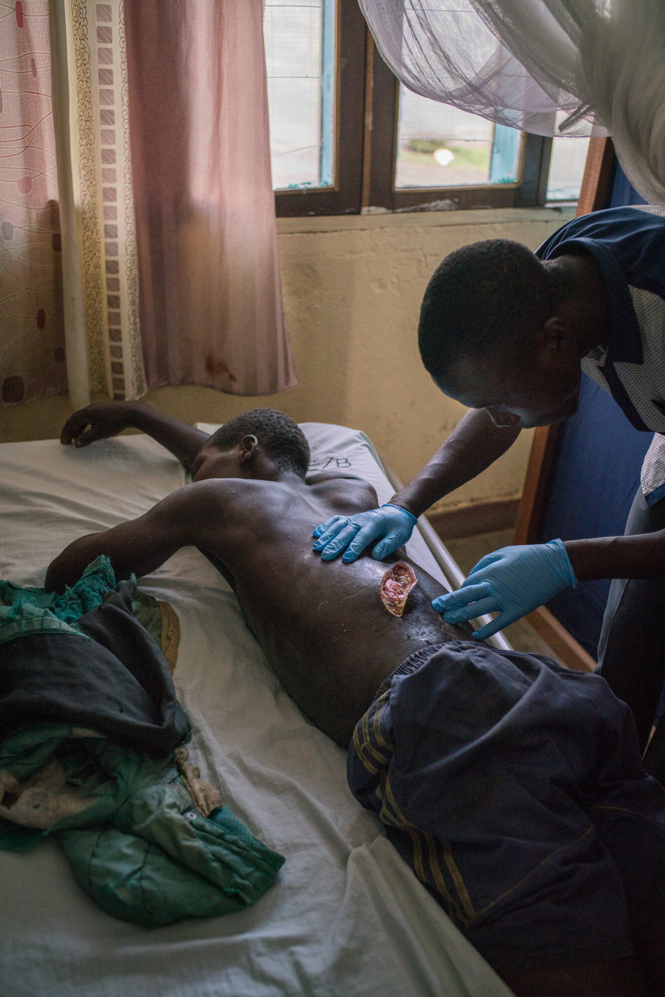  Floribert Lobini, 42, receives treatment for his wounds - a machete slash across his back and a puncture in his arm by an arrow - in the hospital in Bunia. Floribert fled his lakeside village of Dzu when it was attacked on March 12, along with other