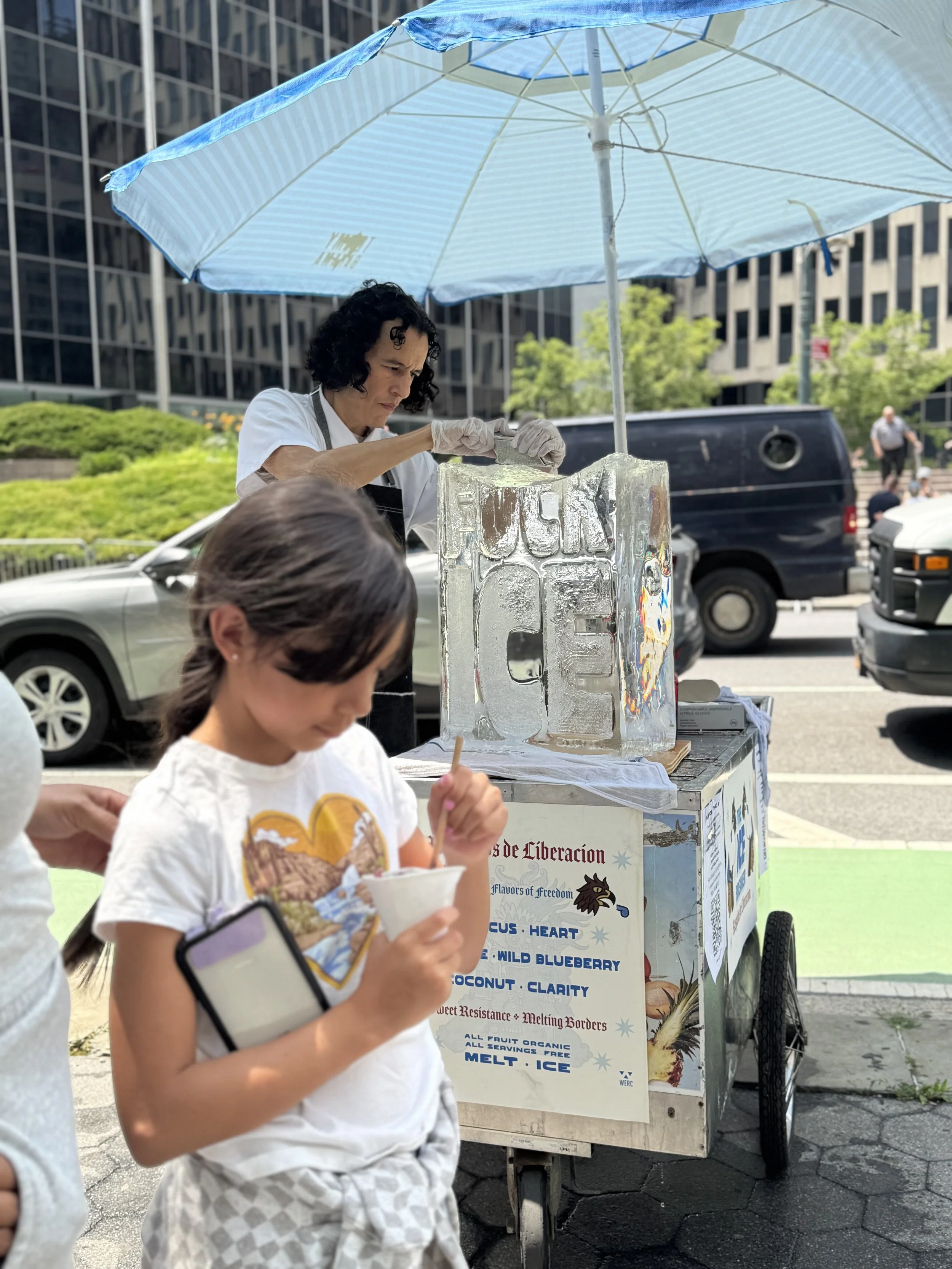 Artist serving raspados from ice block for a ritual offering during Sweet Resistance performance at 26 Federal Plaza, New York City.  2025