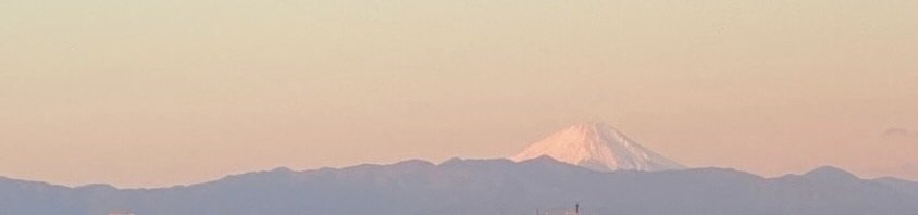Snow topped Mt Fuji behind a dark mountain ridge through a golden sunset creating a feeling of ease and support
