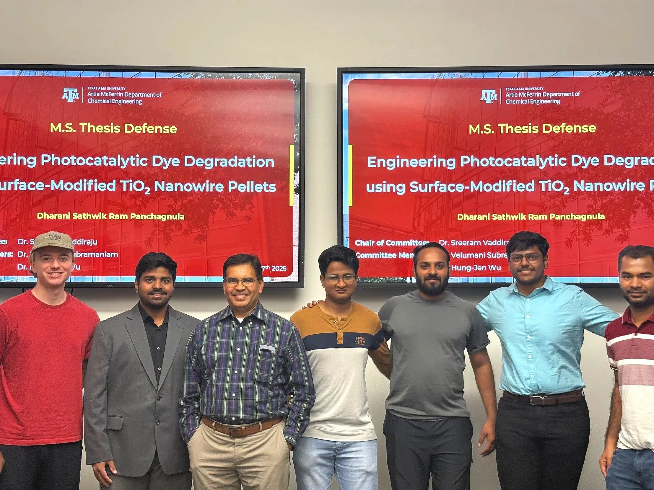 Group of seven men standing in front of two presentation screens displaying research title and author information at Texas A&M University, Artie McFerrin Department of Chemical Engineering, related to engineering photocatalytic dye degradation using surface-modified TiO₂ nanowire pellets.