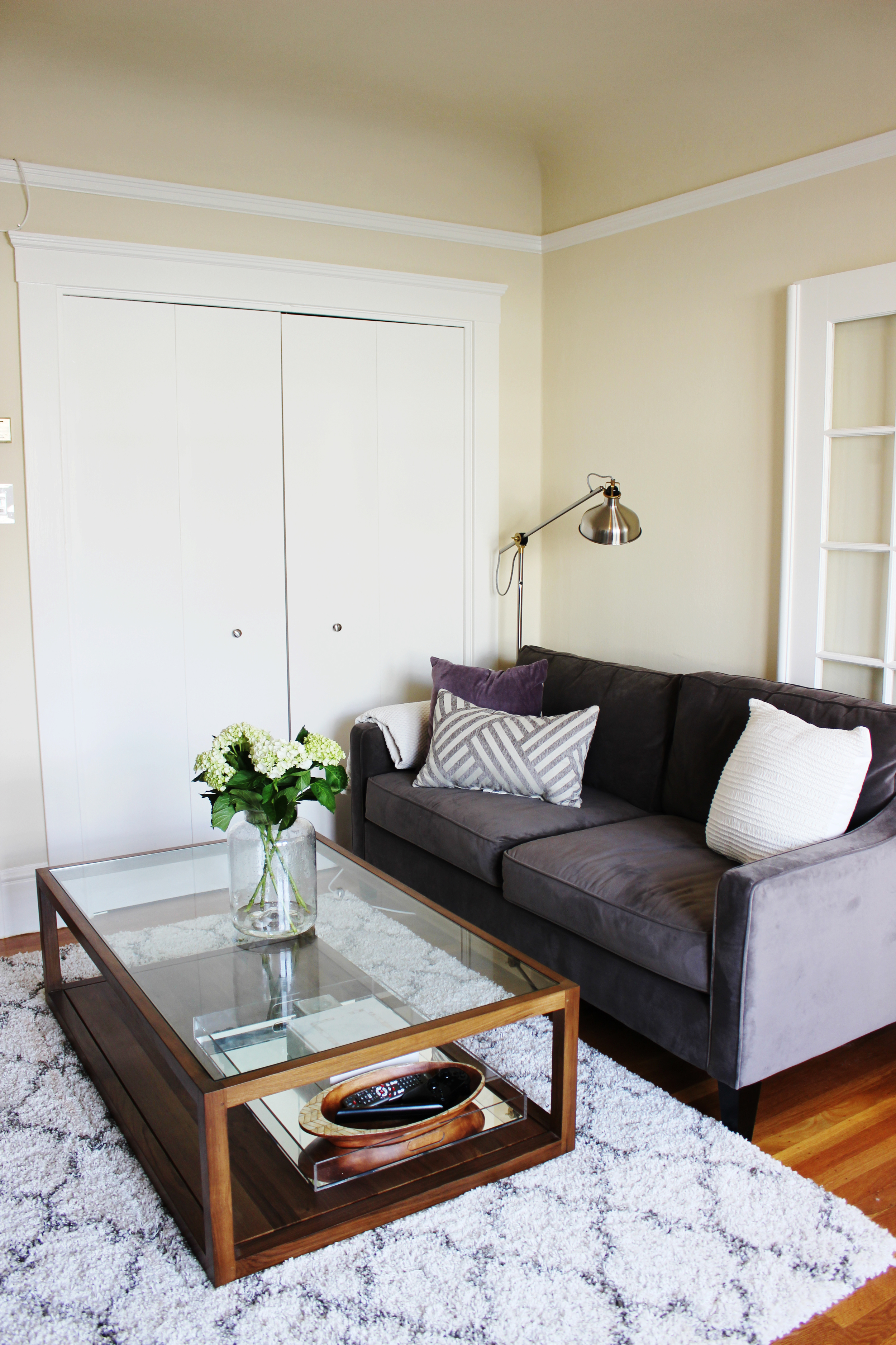 It's polished, bright and sophisticated. You can easily add additional seating for friends with some extra floor cushions. The mirrored lucite tray does double duty by keeping the remotes and other miscellaneous items contained and providing some extra bouncing light with its reflection. We also replaced a console table with a credenza. The console table was perfectly functional, but lacked the storage that the client needed. 
