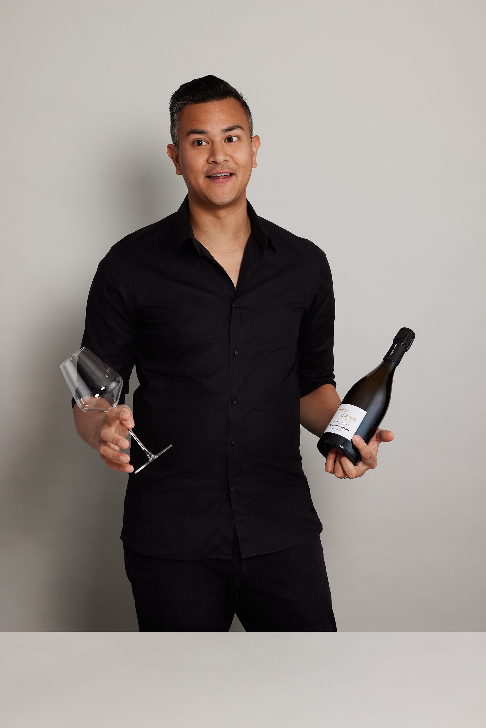 James Dossan of Curated Grapes holding a wine bottle and wine glass speaking off camera with photography by Sarah Anderson Photography.jpg