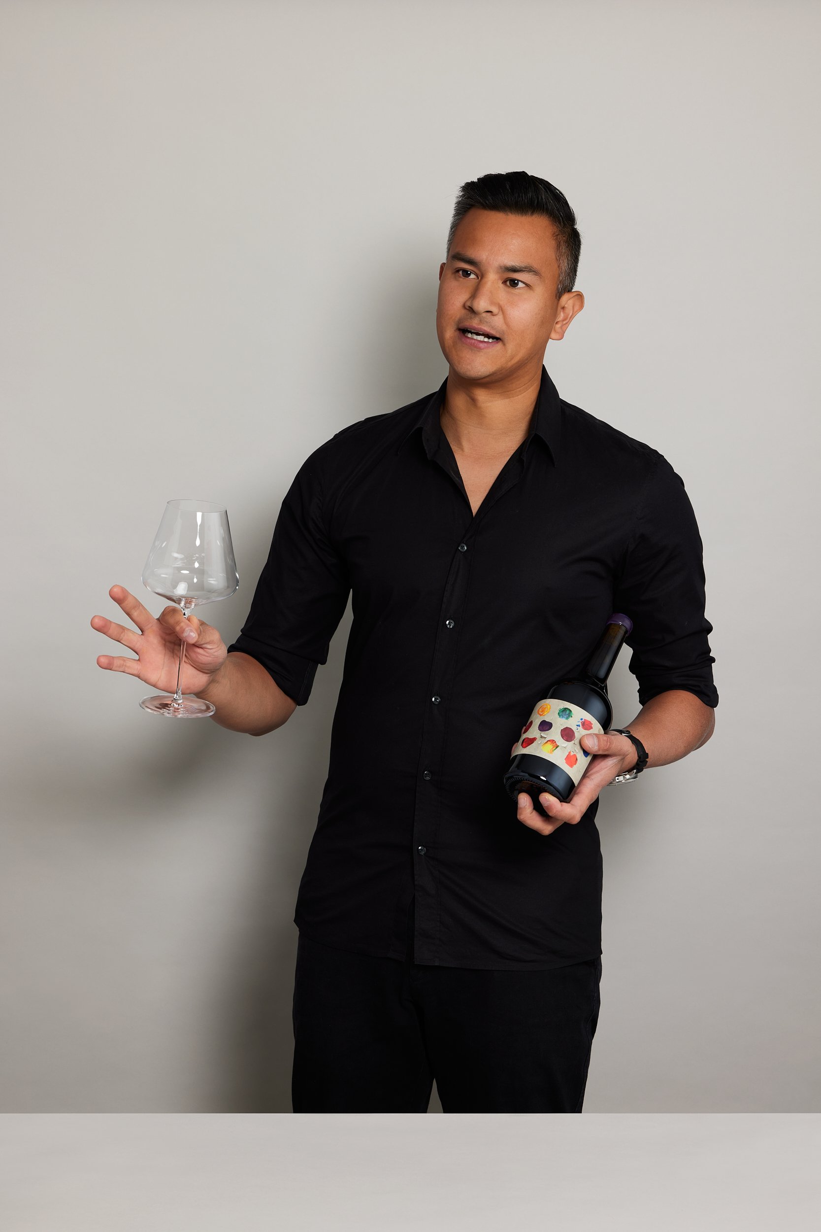 James Dossan of Curated Grapes holding a wine bottle and wine glass talking off camera with photography by Sarah Anderson Photography.jpg