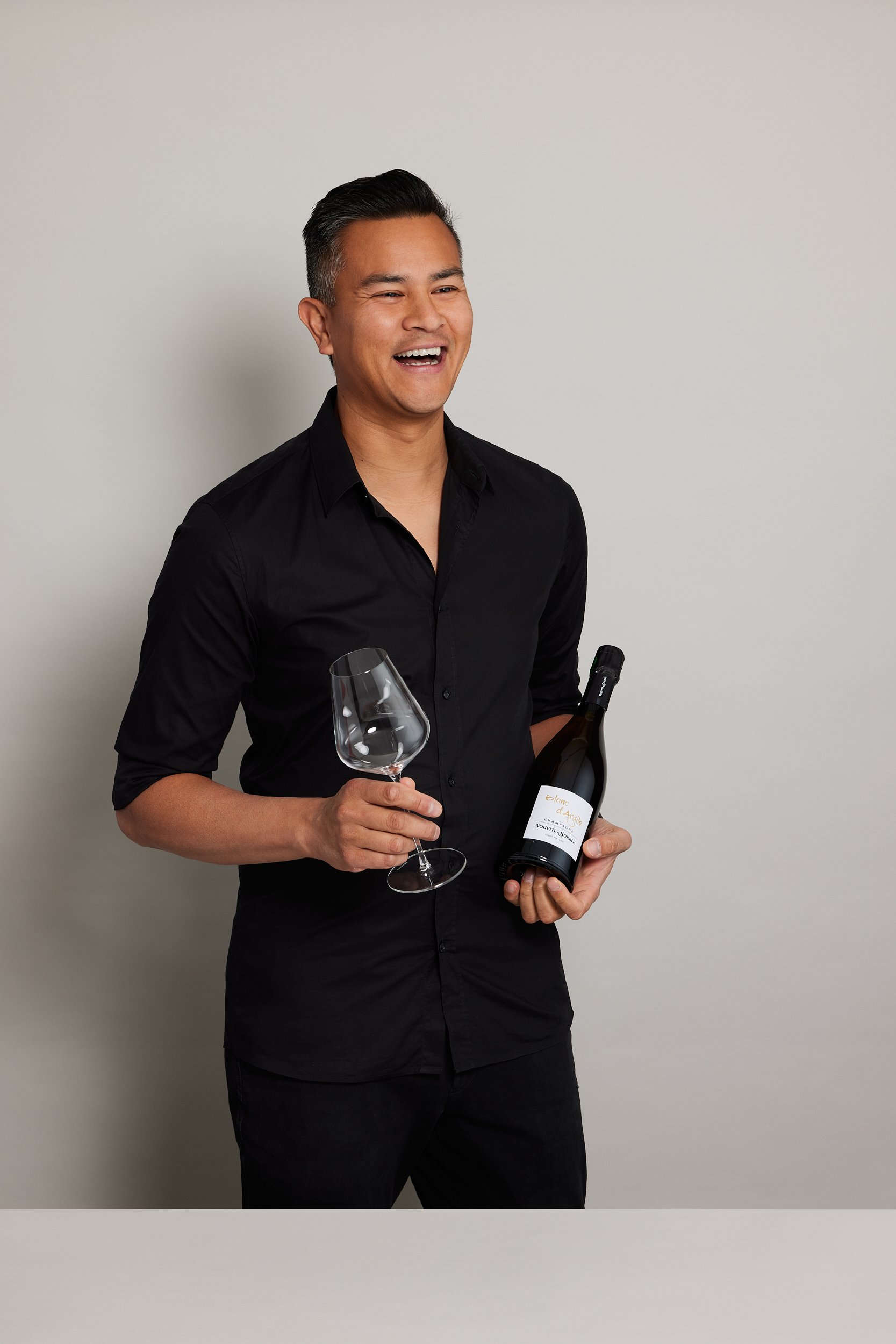 James Dossan of Curated Grapes holding a wine bottle and wine glass laughing off camera with photography by Sarah Anderson Photography.jpg