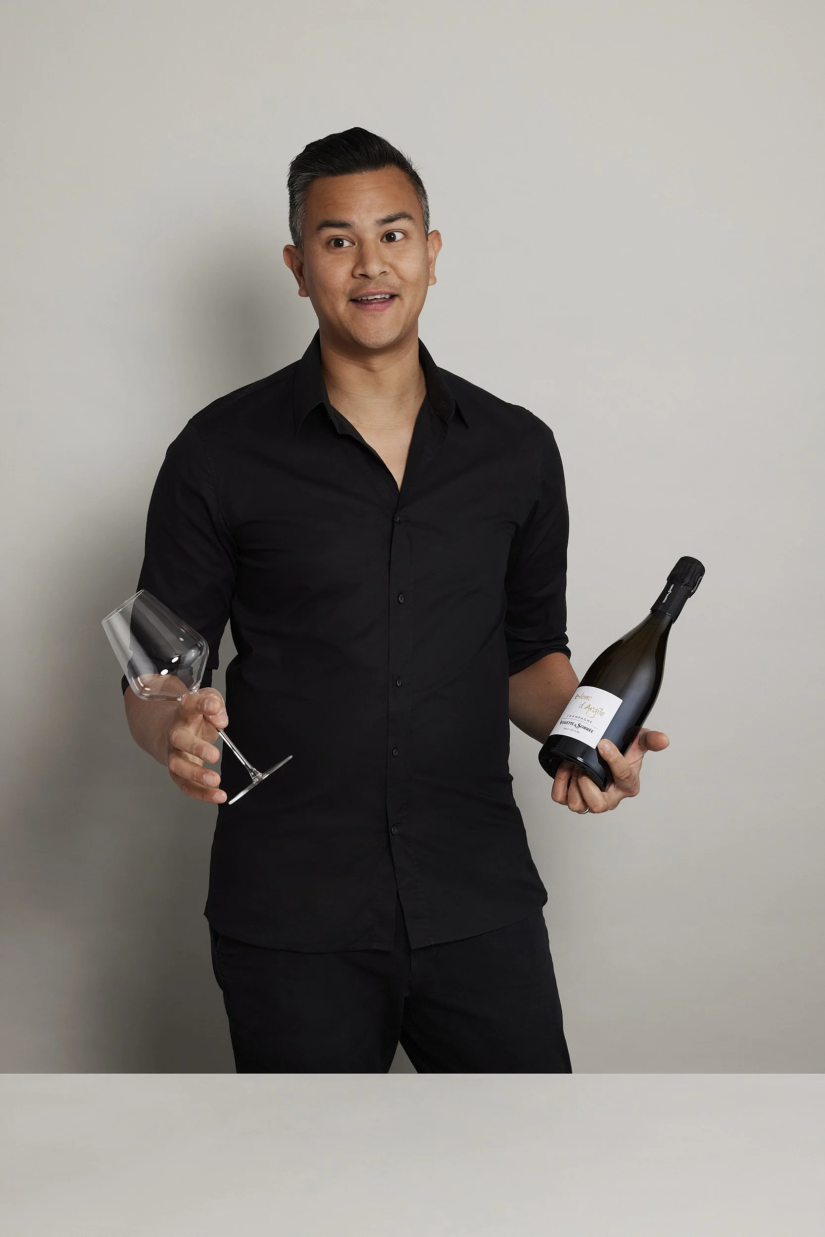 James Dossan of Curated Grapes holding a wine bottle and wine glass speaking off camera with photography by Sarah Anderson Photography_Web.jpg