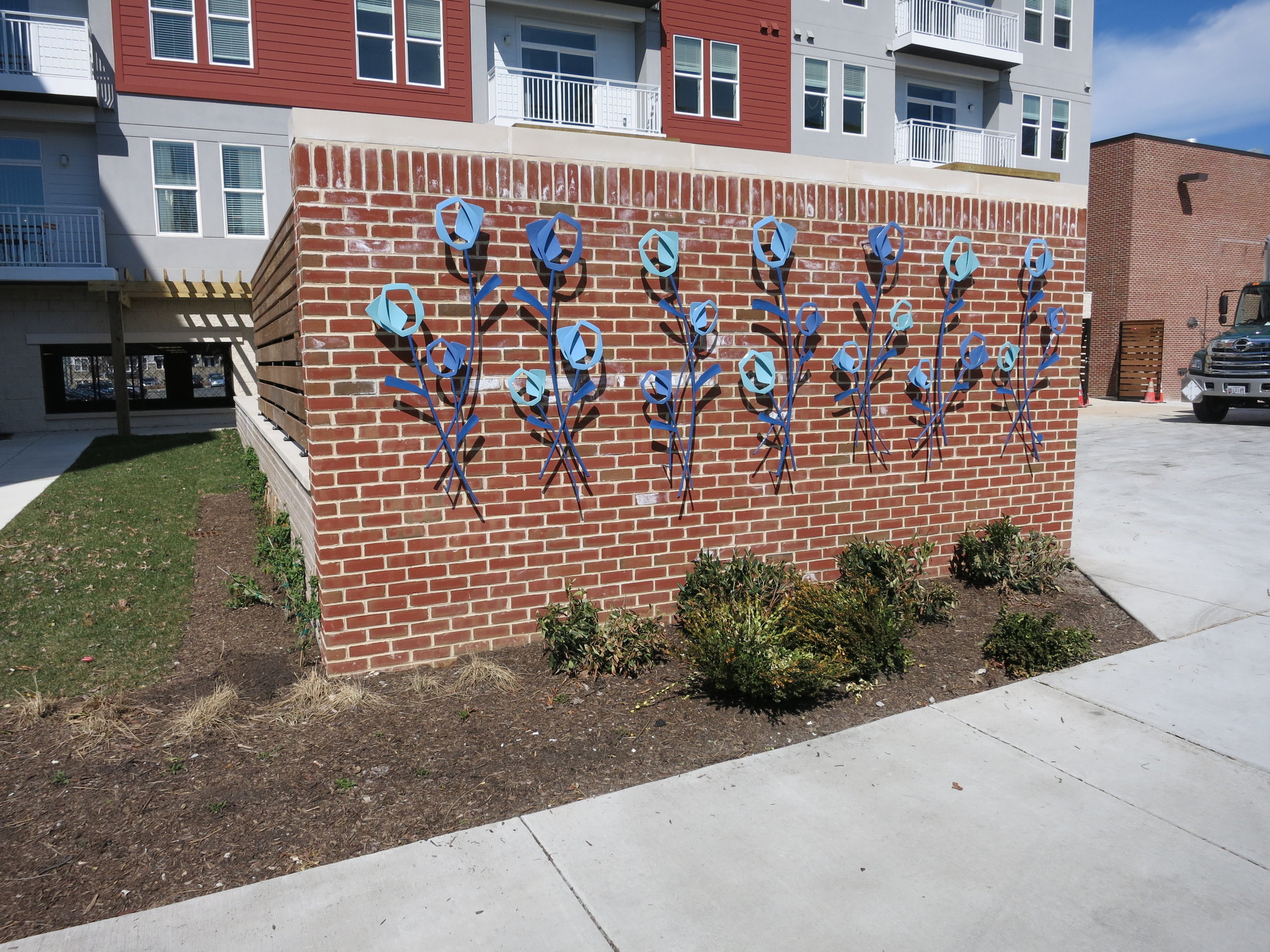 Our installers had to individually mount each welded and powder-coated flower to the brick wall. 