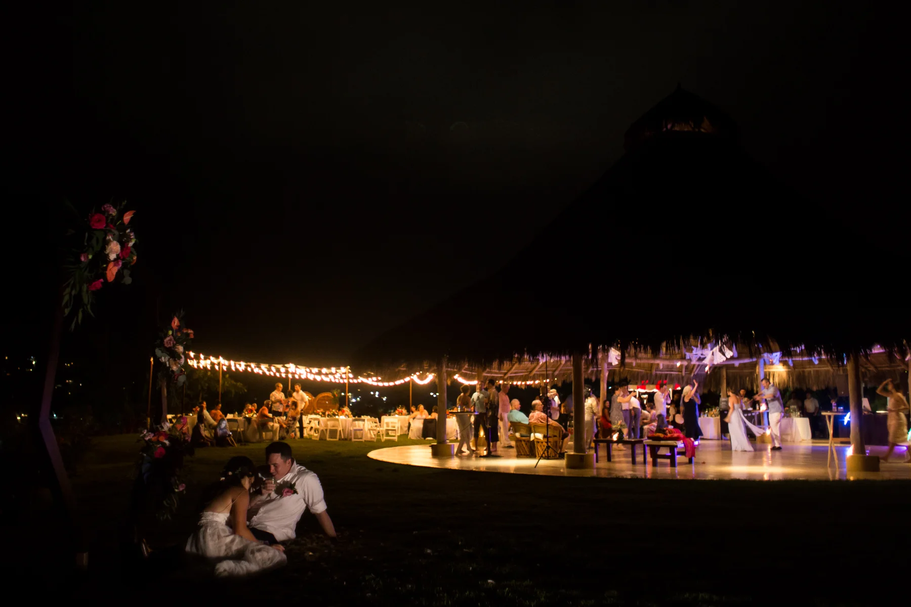A bride and groom sit outside the palapa while their reception goes on. Photo by Erin Parker.