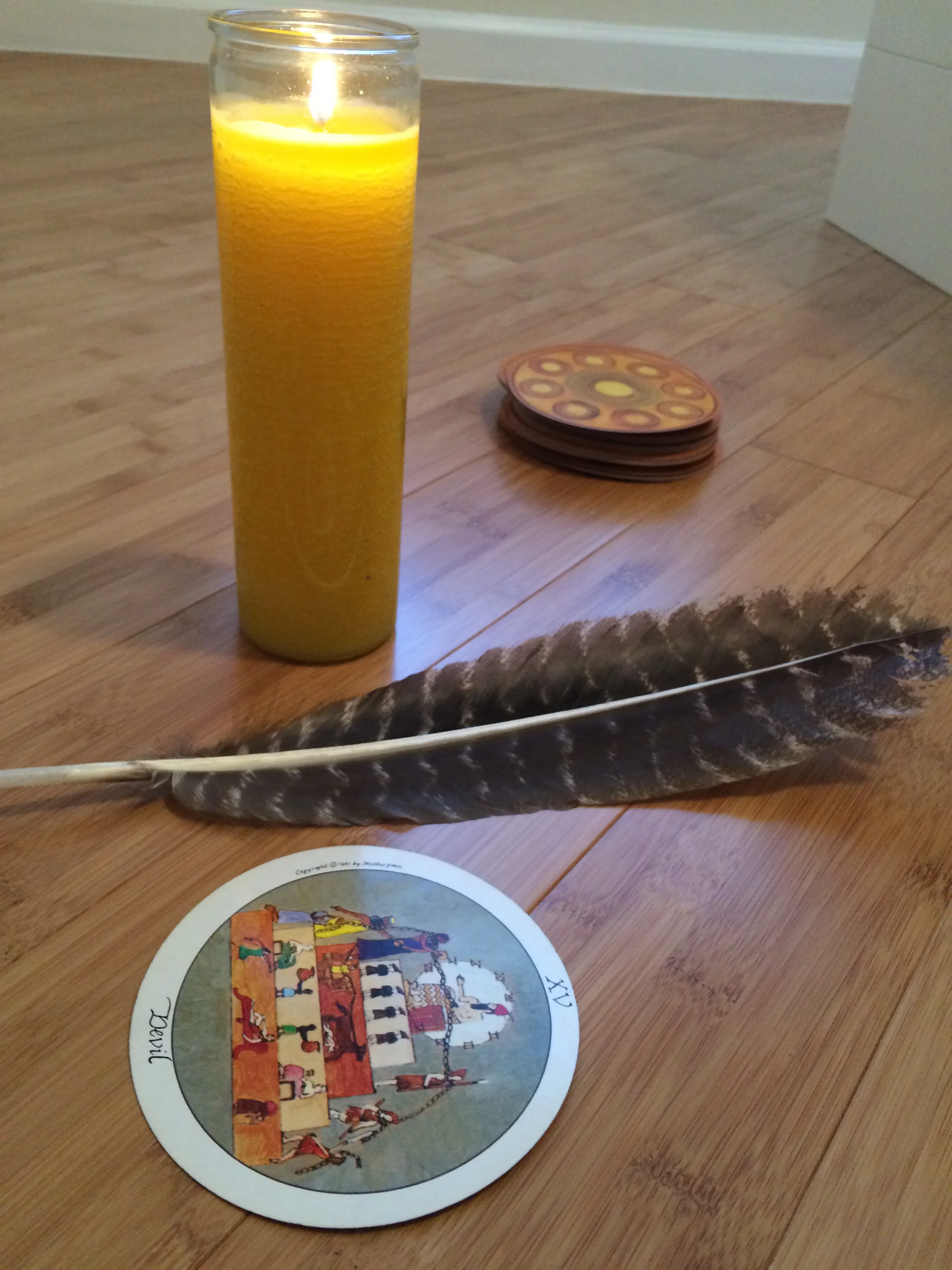 Devil card chillin' with my shaman feather and lit full moon candle with Motherpeace deck stacked in background