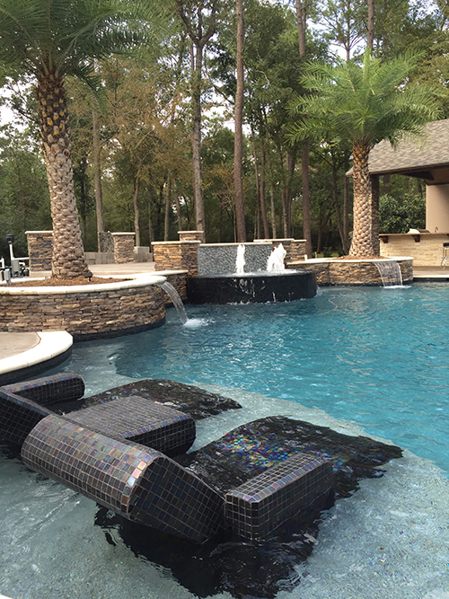 custom-pool-builder-custom-pool-the-woodlands-spring-houston-glass-tile-built-in-lounge-chairs-pebble-tec-palm-planters-stacked-stone-best-pool-builder-limestone-travertine-coping-stamped-concrete-salt-finish.jpg