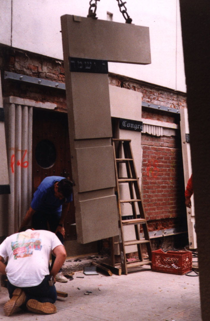 The renovation of this historic synagogue included the installation of a new revetment of precast concrete panels hung from a steel ledge. The concrete "tablets" are inset with malachite strips engraved with Hebrew text and fitted out with bro