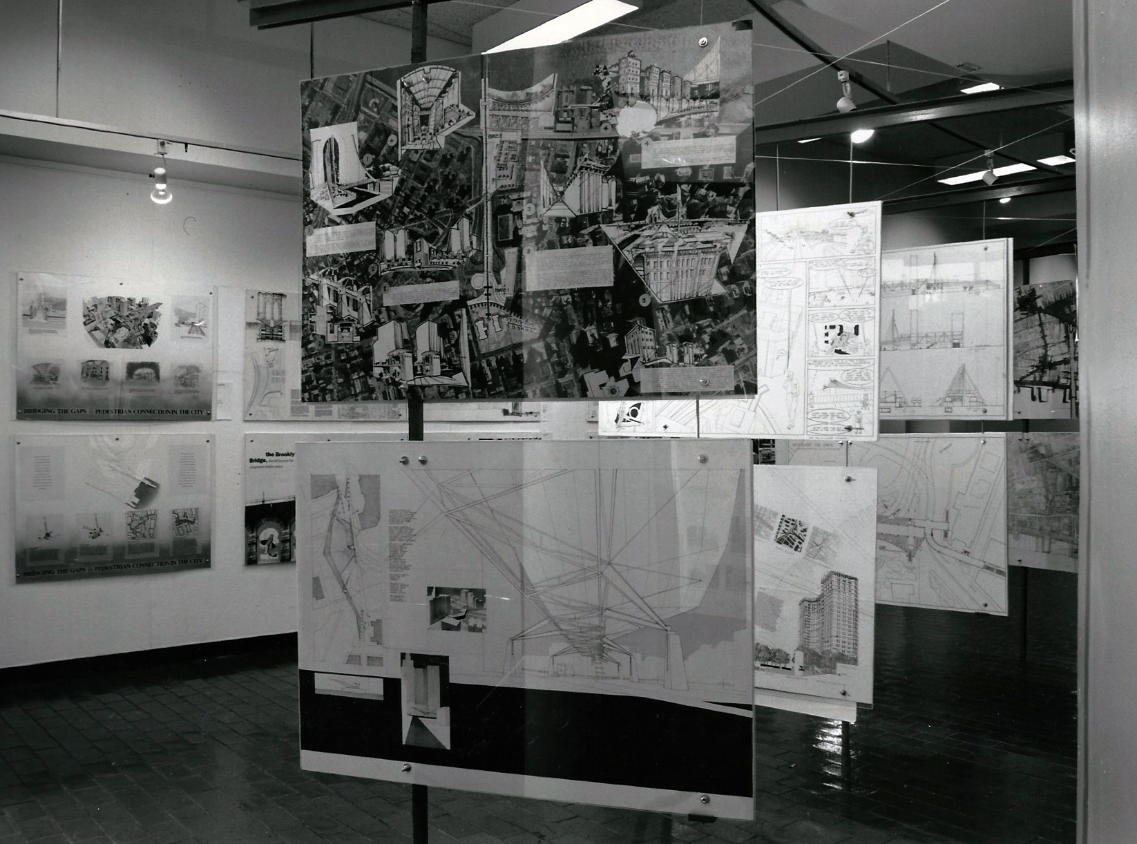 For this study in the pedestrian connection of the Brooklyn Bridge to Lower Manhattan, we developed a stanchion system of steel L-sections, bolts and guy wires with the feel of the light and small redundant members of the historical bridge. The installation turned the space outside of the auditorium space of the Graduate School of Architecture and Planning , Columbia University into an informal gallery. The stanchion system was flexible and useful enough that it remained in place for almost ten years after the show and displayed any number of exhibits.