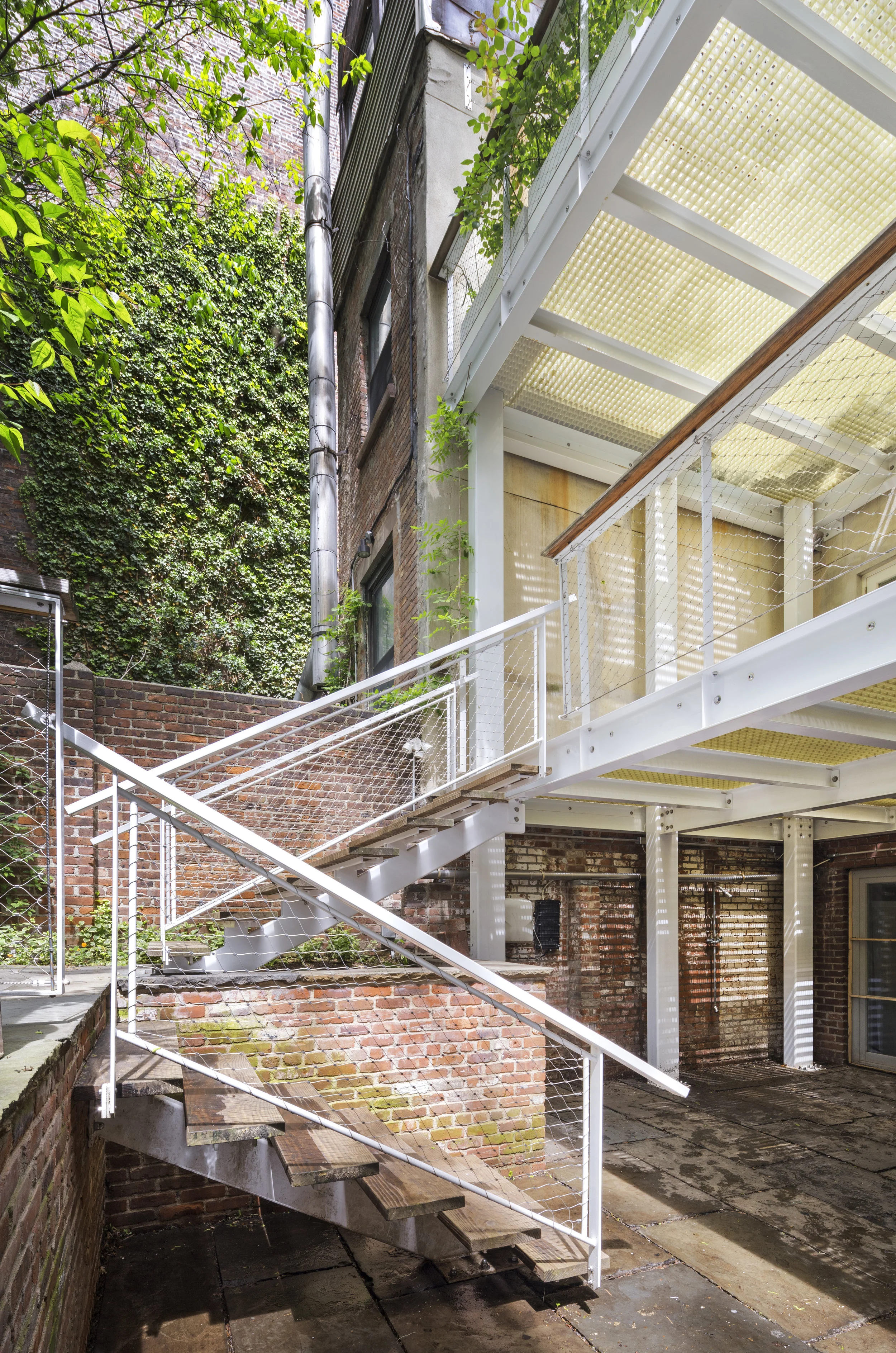 The artist who lives and works in this house desired a porch large enough to use as an outdoor studio. The dining room and kitchen open onto its top level; the studio office and library open onto the lower porch. The stone dining court installed ben