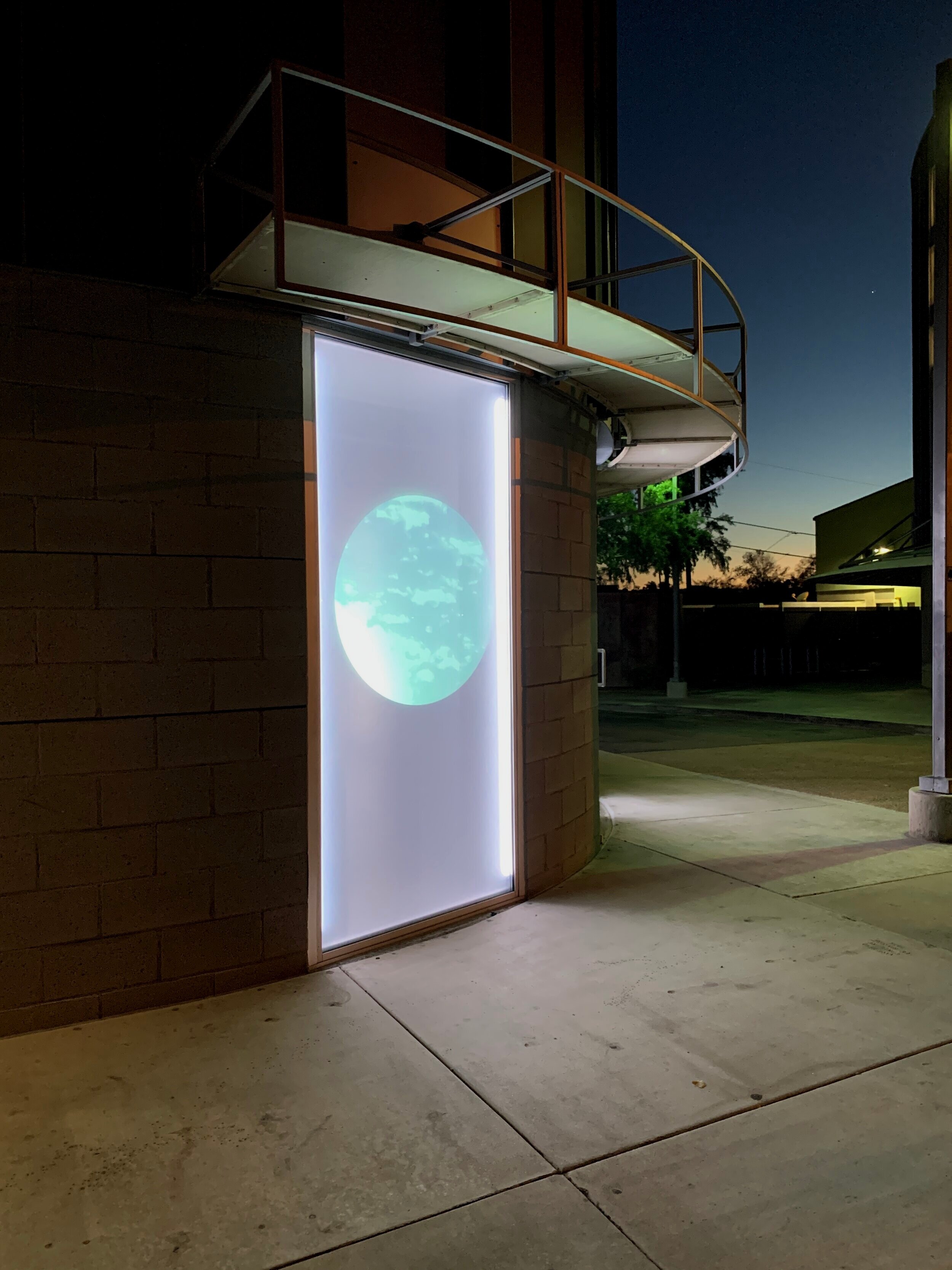 the sky in a circular cutout projected through a window onto a screen seen from the street at night