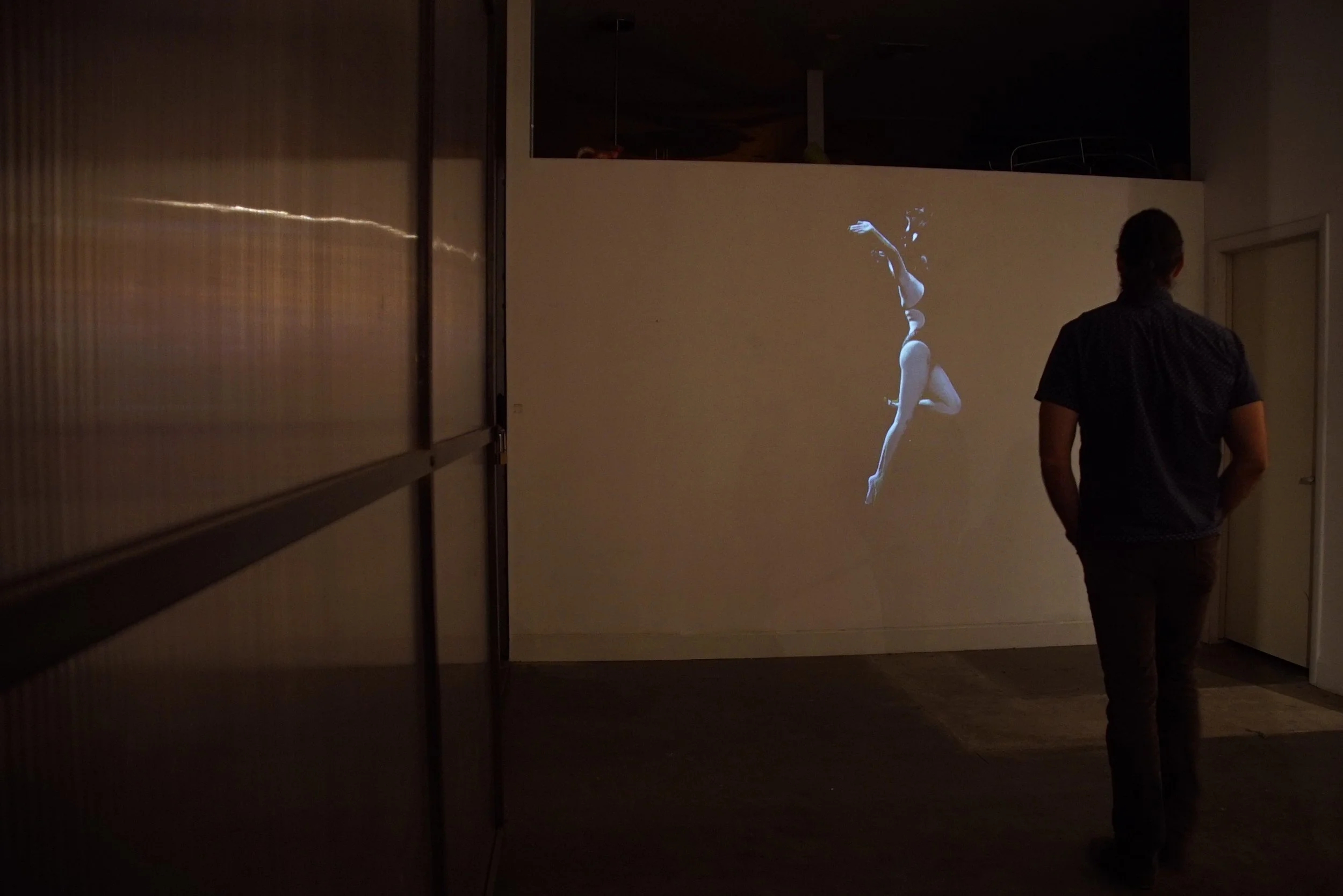 Still from Groundwater showing the artist suspended underwater in an immersive video projection installation.